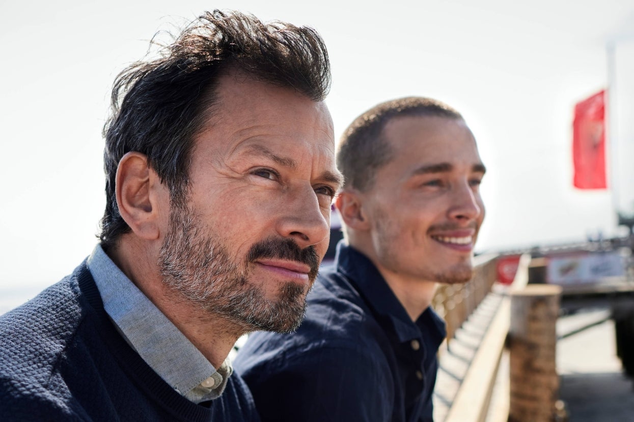 Two people smiling while looking into the distance. They appear relaxed and content, suggesting a moment of well-being and positivity