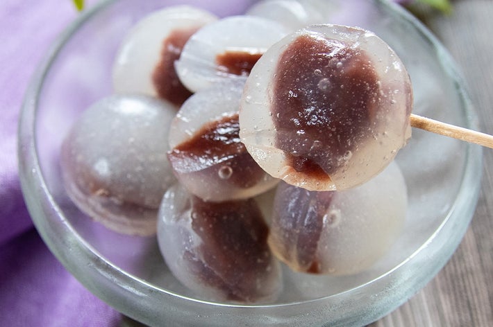 透明な寒天に包まれた小豆入りの水まんじゅうが楊枝に刺さってガラスの器に盛られている。