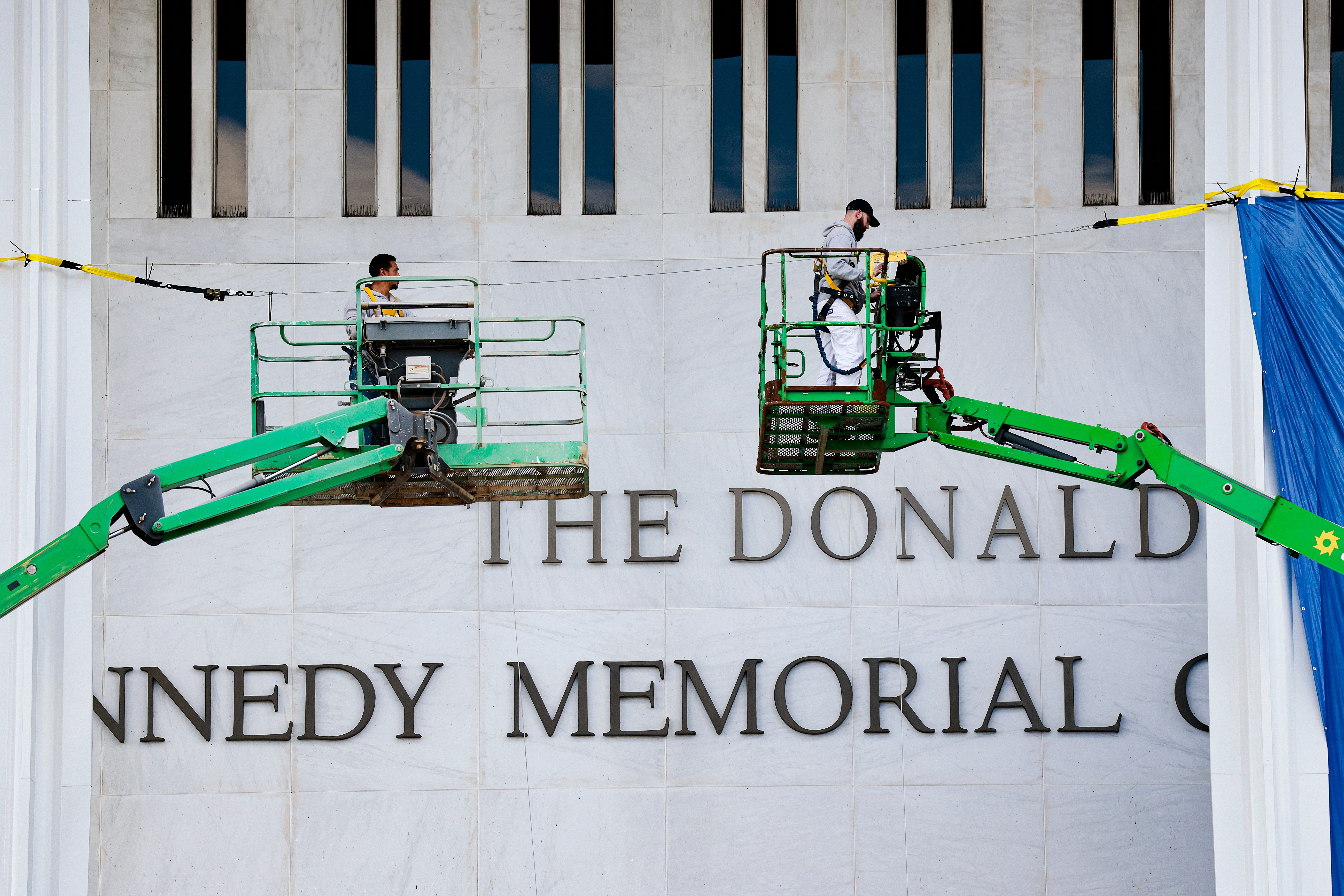 Two workers successful aerial lifts screen up portion of the Donald J. Trump sanction connected the Kennedy Memorial facade