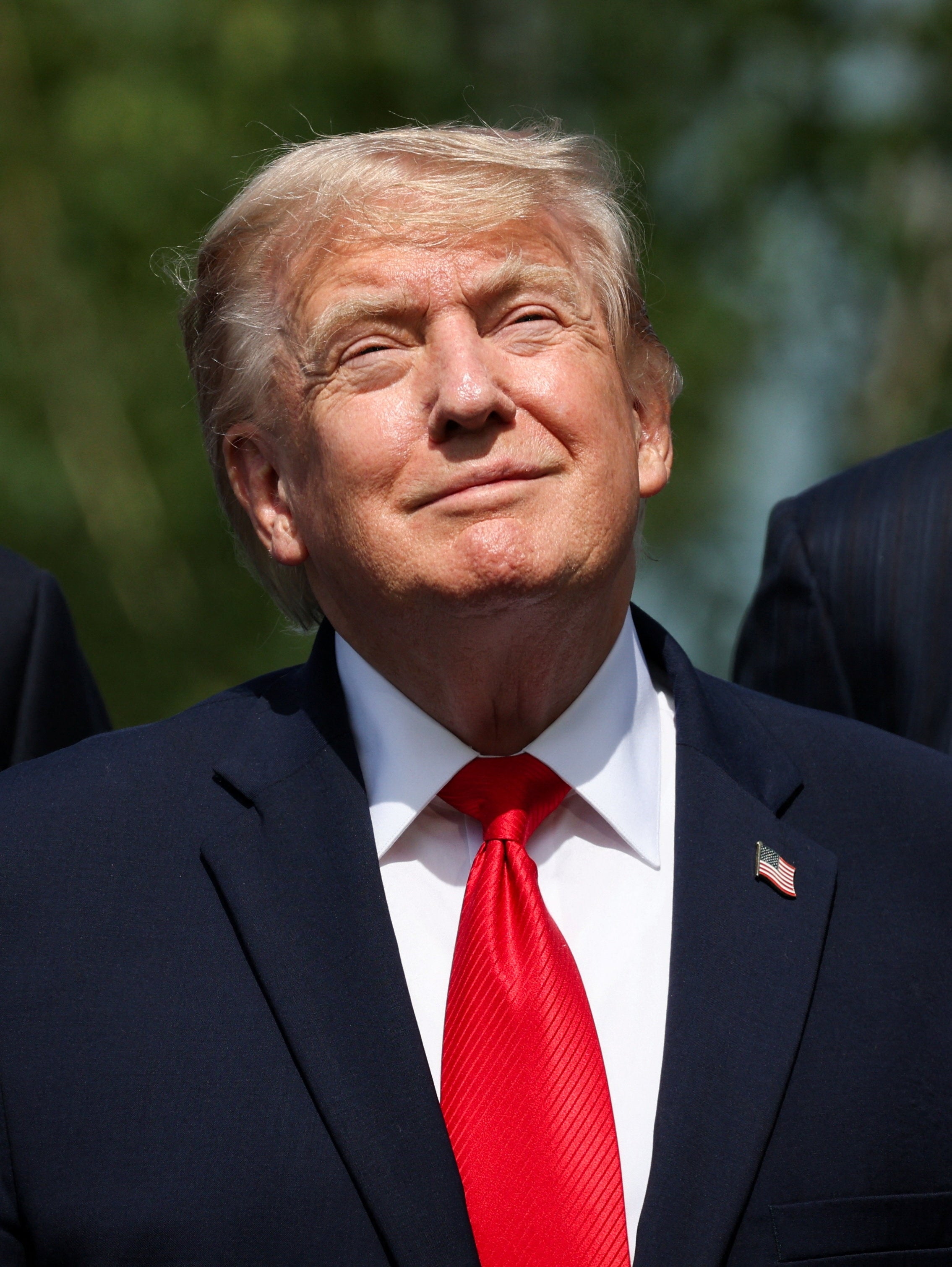 Man successful a suit and reddish necktie looking upward with a flimsy smile