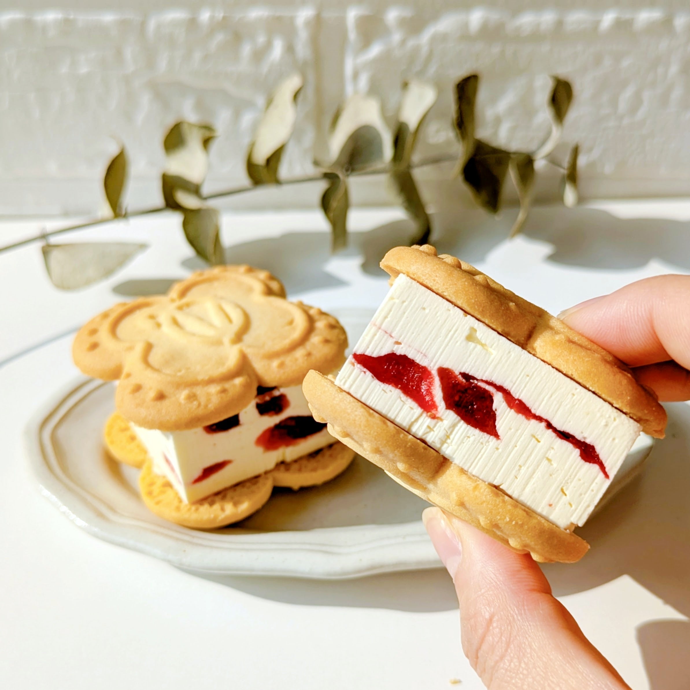 VERY RUBY CUT（ベリールビーカット）「いちごバターサンド」バターサンドクッキーを手に持ち、クリームといちごジュレが挟まれた断面が見える。