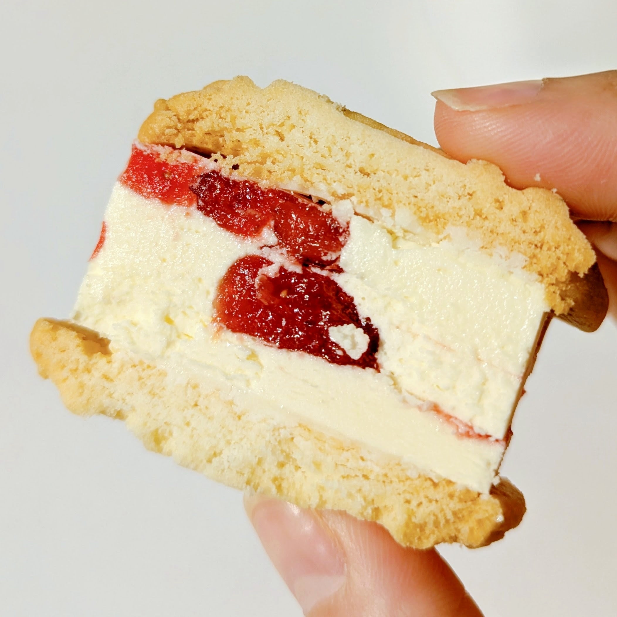 VERY RUBY CUT（ベリールビーカット）「いちごバターサンド」バターサンドが手で持たれている。ホイップバタークリームとイチゴジュレがクッキーで挟まれている。