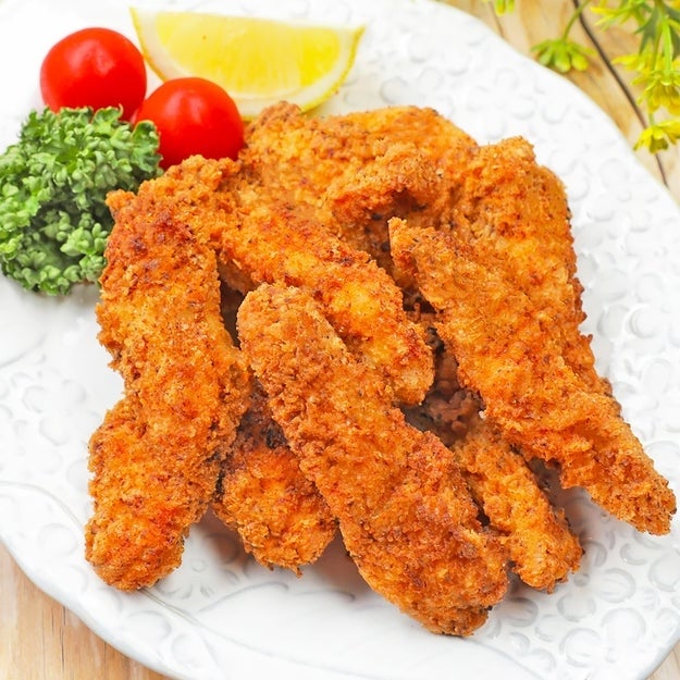 皿に盛られた揚げた鶏肉、付け合わせにレモン、トマト、ブロッコリー。