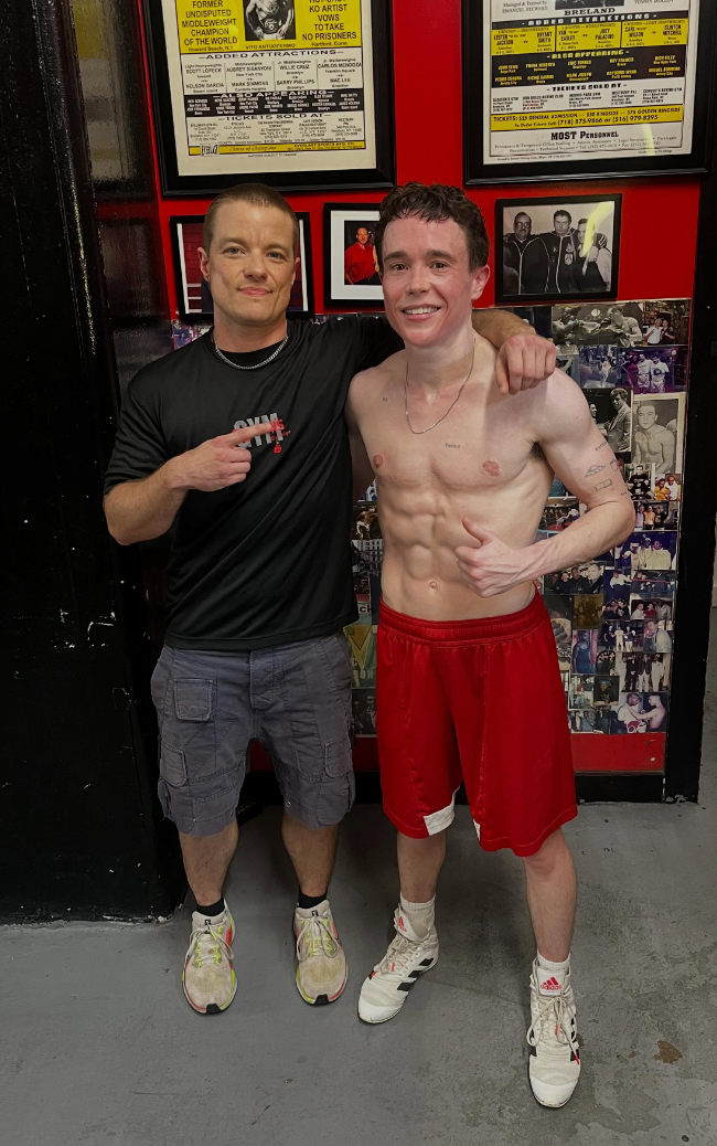 Elliot and his manager  posing successful  a gym. Elliot is shirtless successful  diversion  shorts, showing defined abs