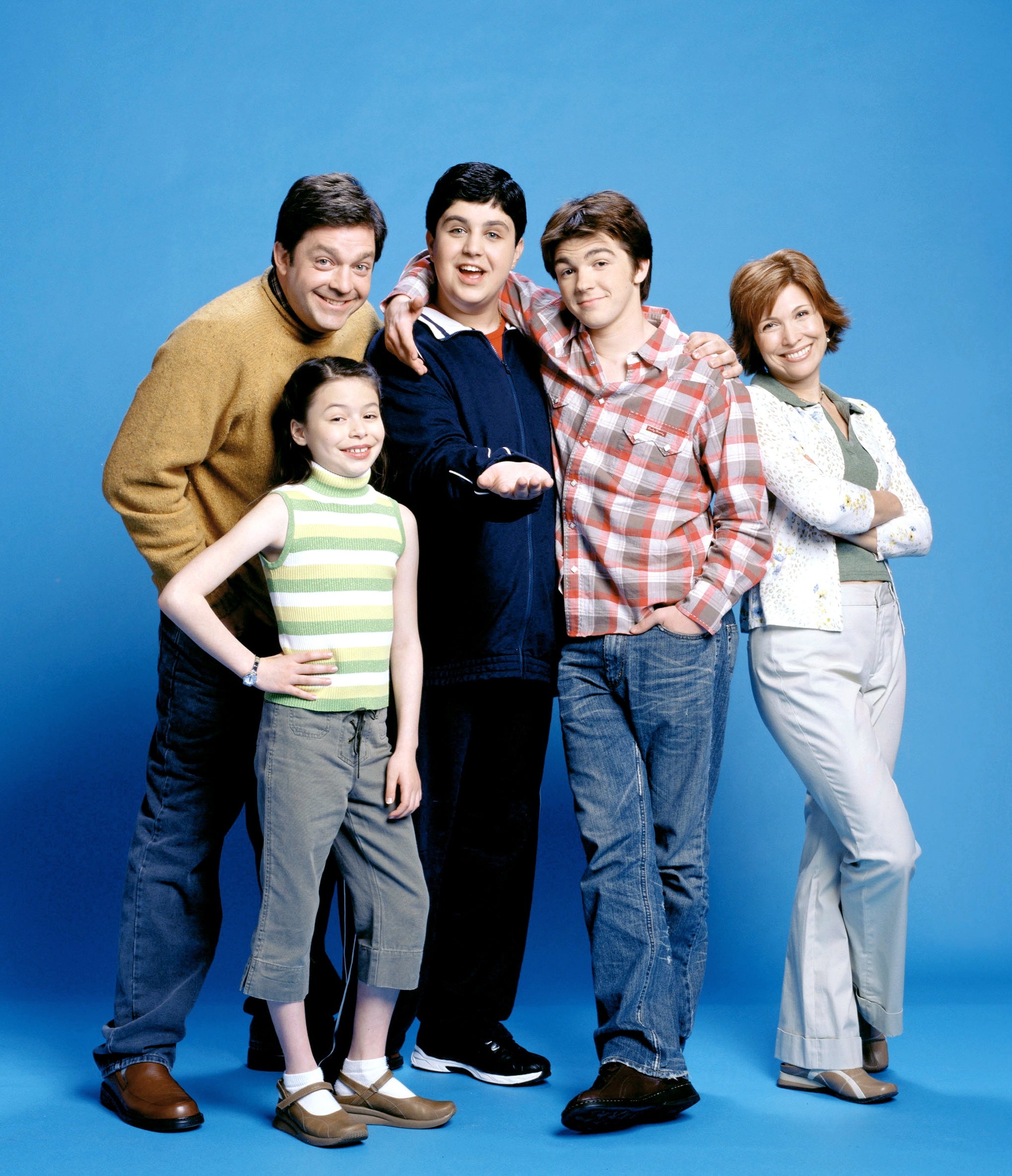 Group of 5  radical   posing, including 2  adults and 3  teenagers; 1  teen   wears a plaid shirt, different  wears a acheronian  jacket, a miss  wears a striped top
