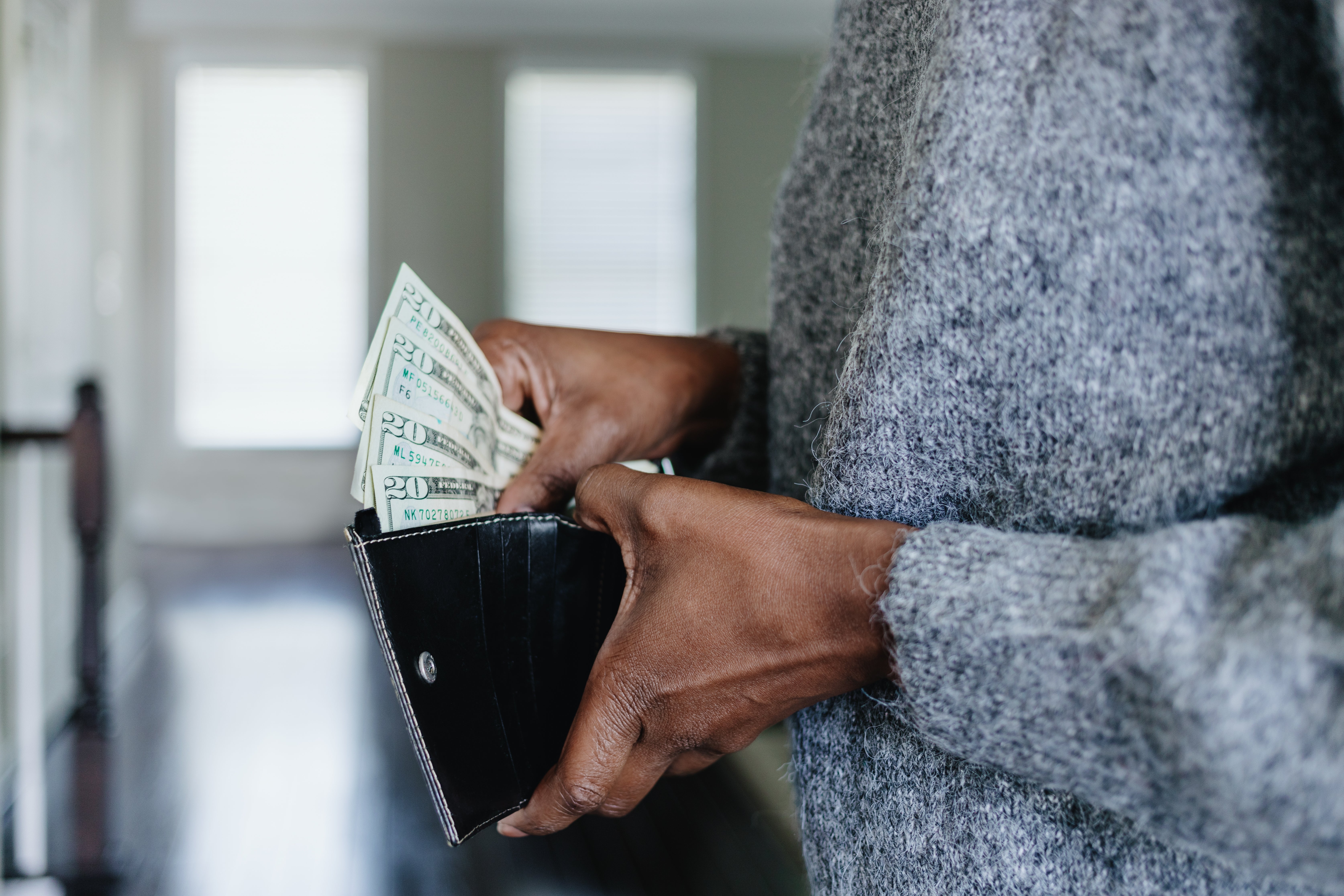 Person holding respective 20-dollar bills, placing them into oregon taking them retired of a wallet