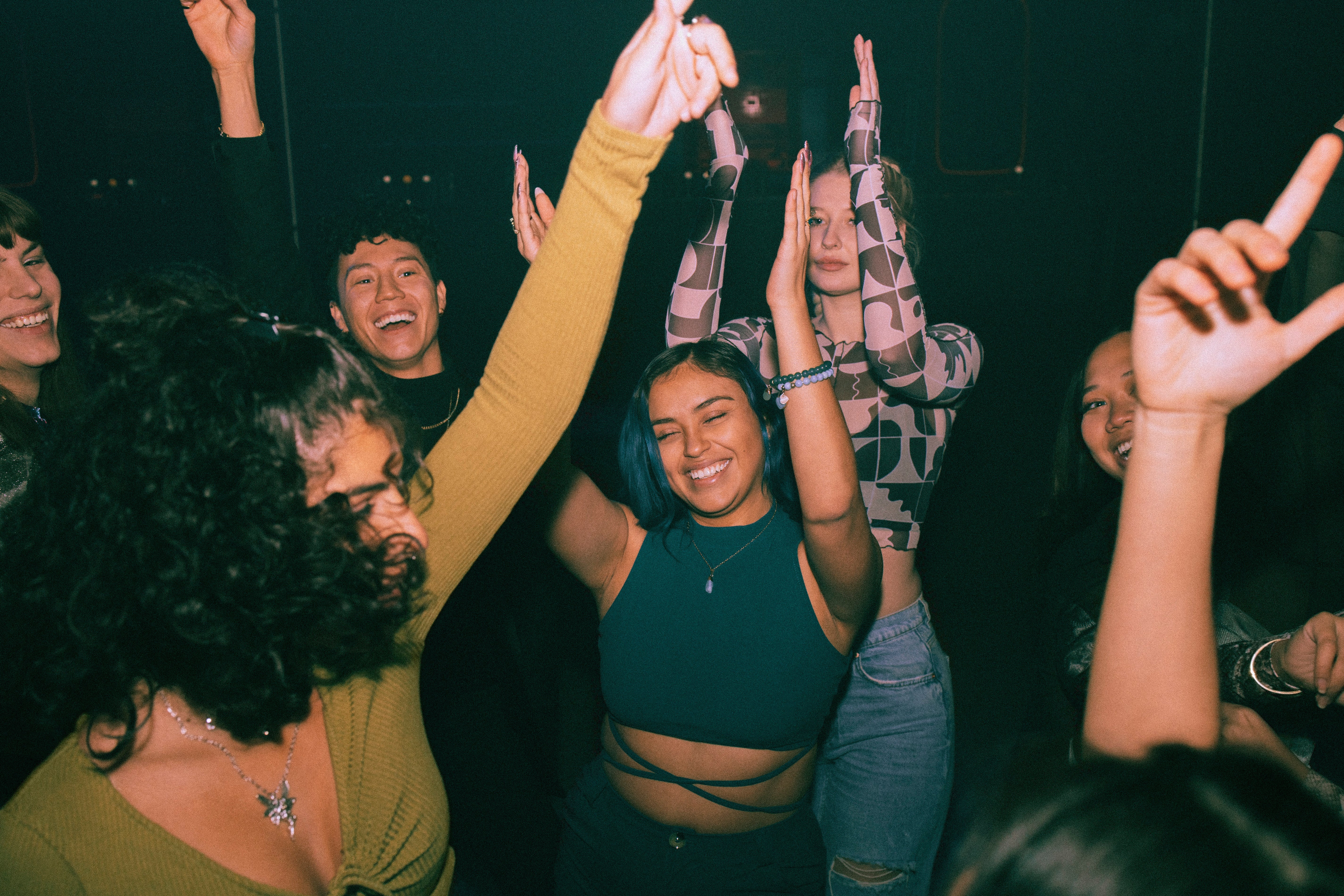 A radical of radical energetically dancing successful a club, smiling and raising their hands