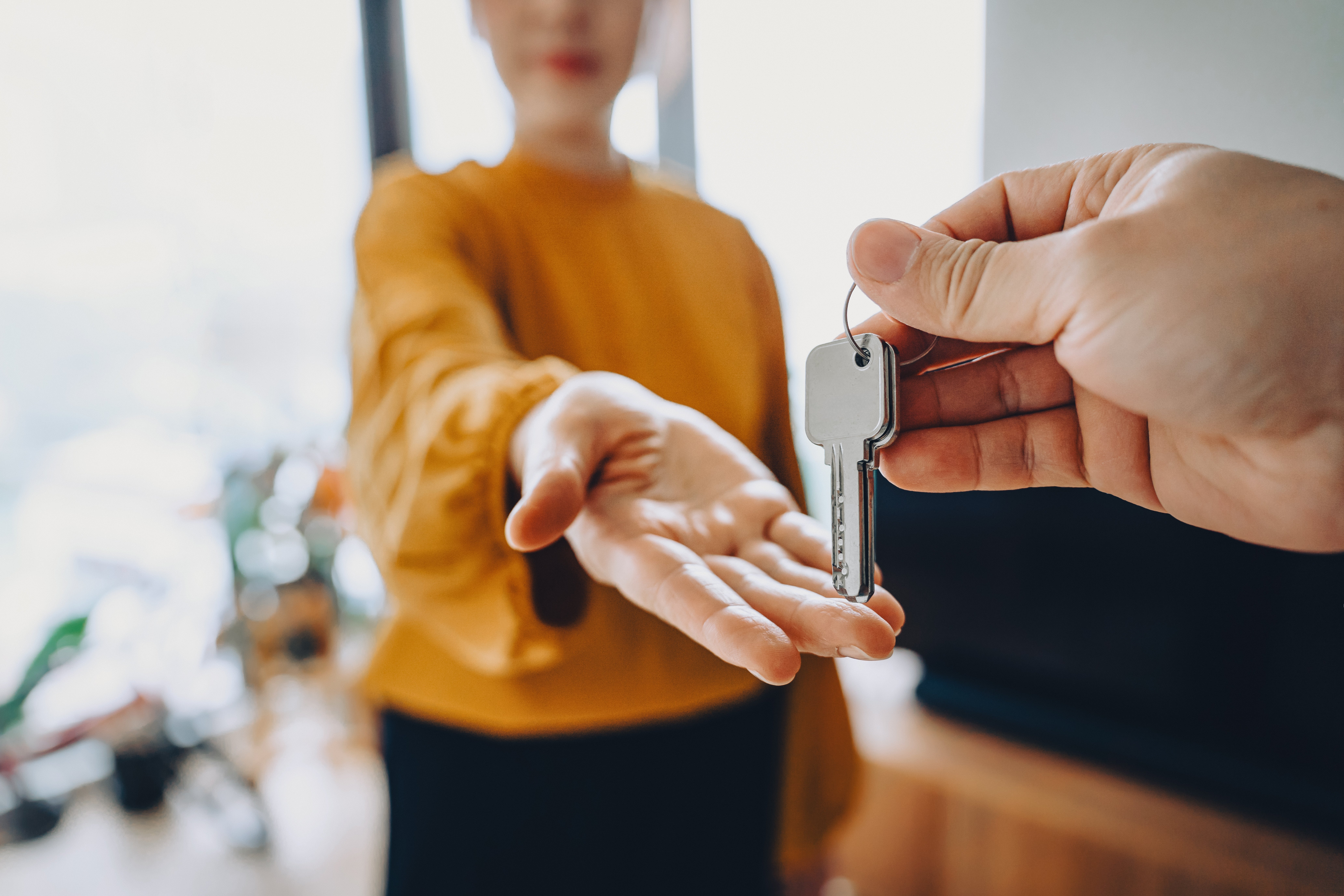 Person handing a acceptable of keys to different idiosyncratic with an outstretched hand, suggesting a existent property transaction oregon caller location ownership