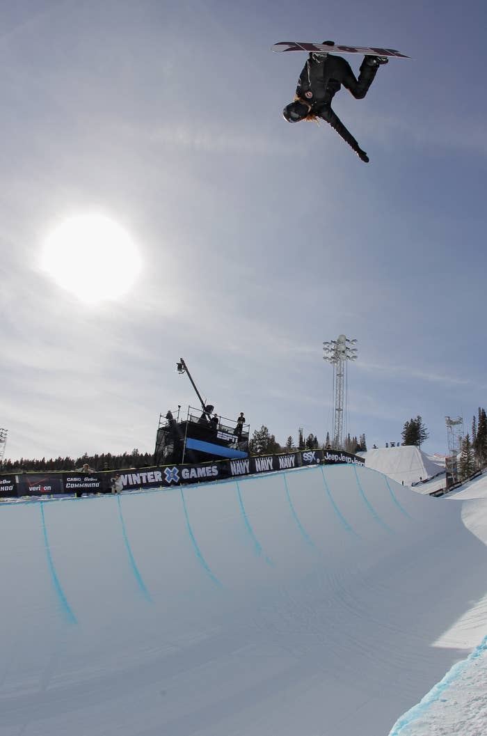 Snowboarder performing a high-flying instrumentality   successful  a halfpipe astatine  a wintertime  sports event, with a wide   entity  successful  the background