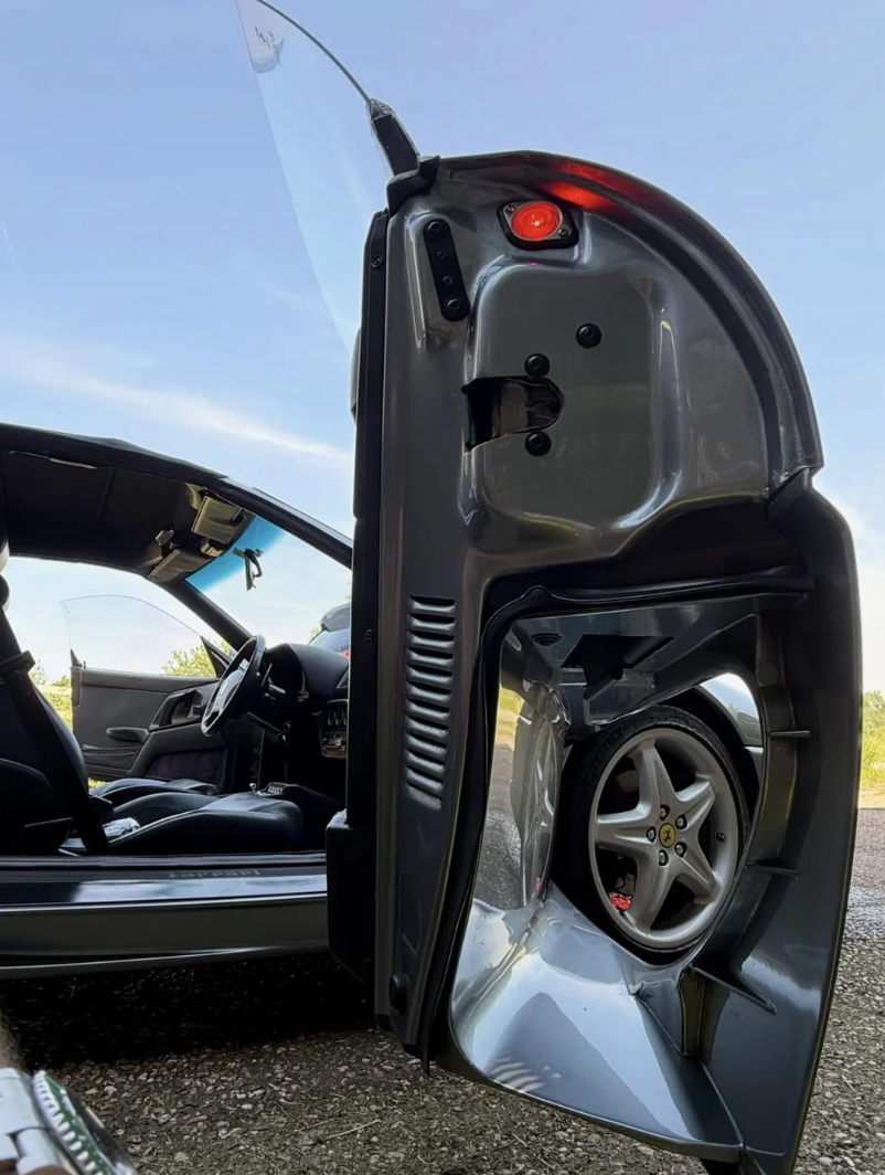 Car door open, showing intricate design with a wheel incorporated in the door. Interior of car visible, highlighting unique door engineering