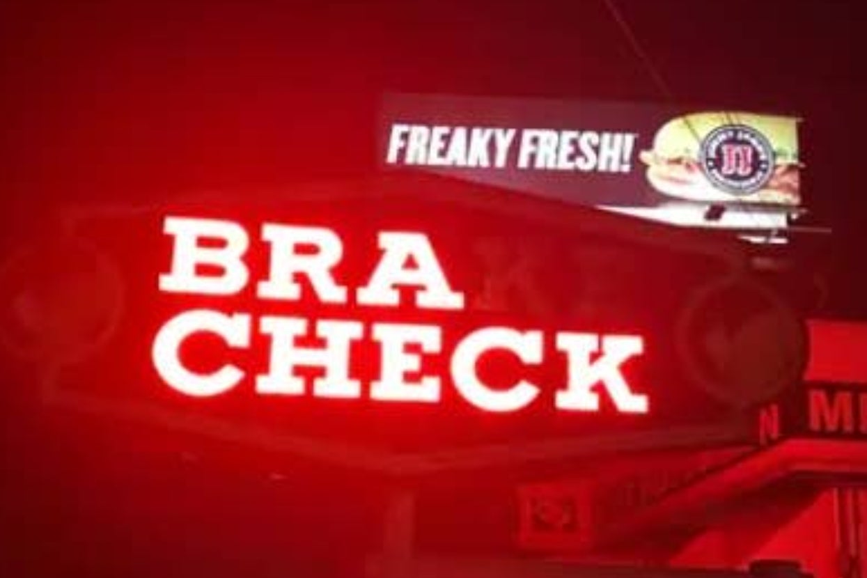 A neon sign reads "BRAKE CHECK"; a billboard above says "FREAKY FRESH!" with a sandwich image