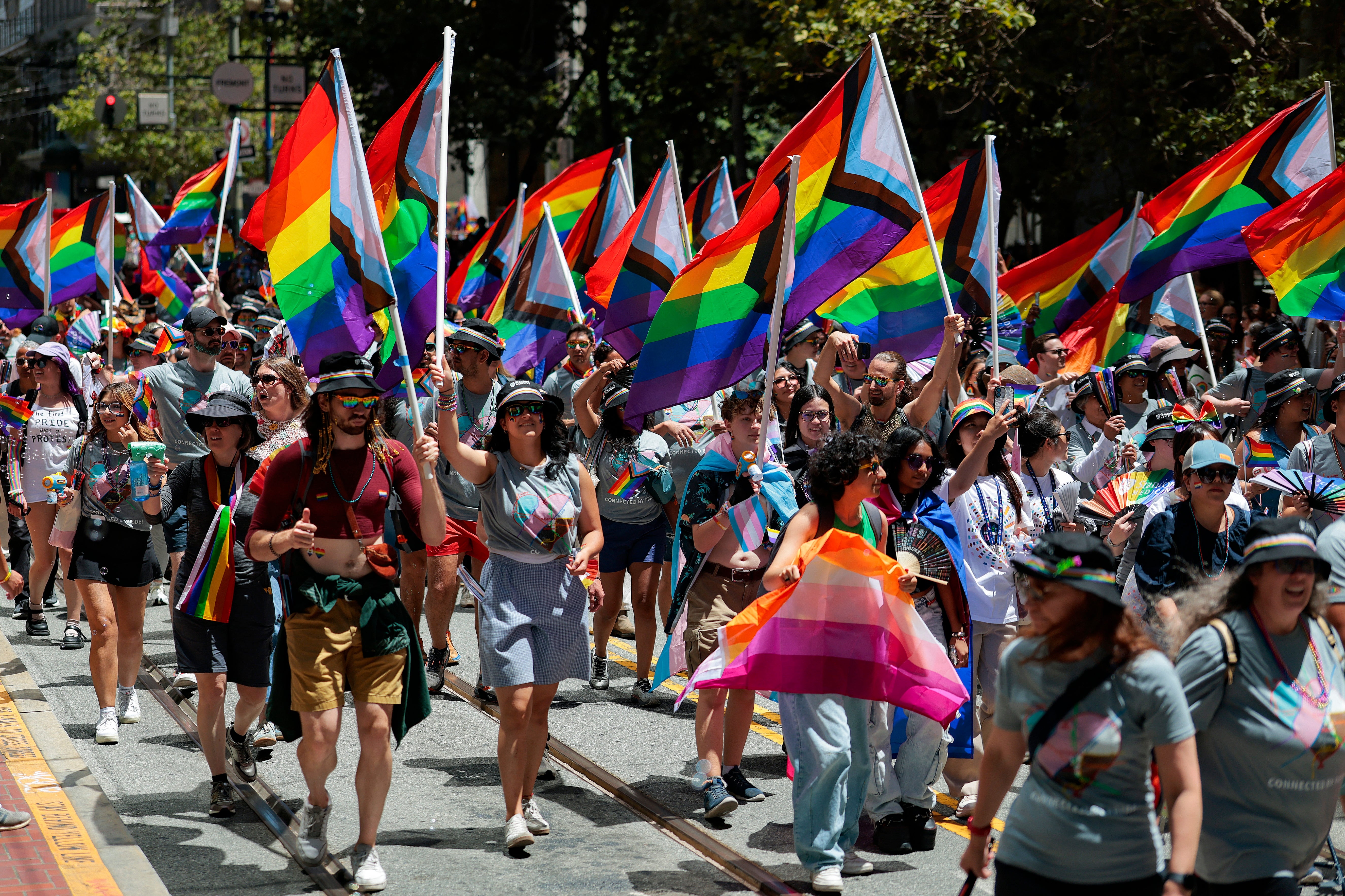 People marching successful a thoroughfare parade, waving pridefulness flags. Some deterioration hats and casual clothing. The country is festive and celebratory