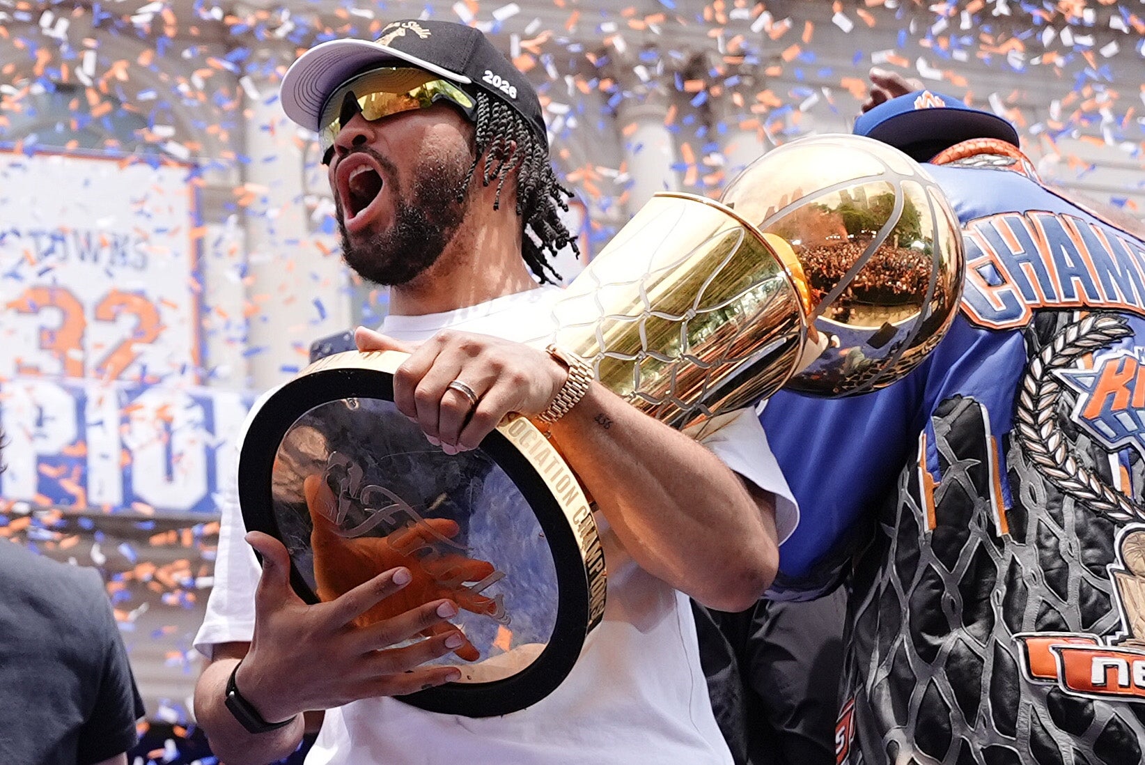 Person celebrating with a ample trophy, wearing a headdress and sunglasses, amid falling confetti astatine a nationalist event