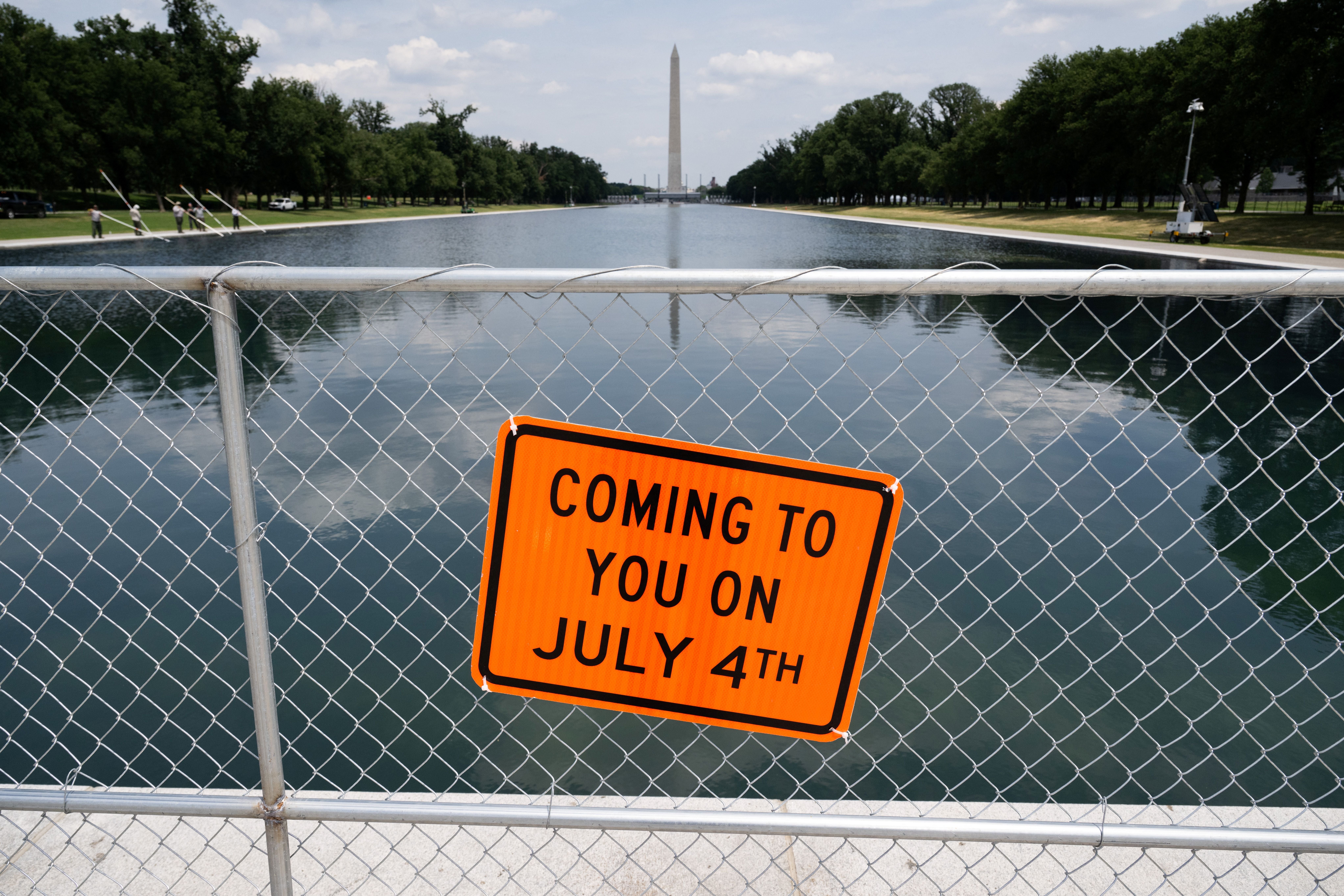Sign connected a obstruction reads "Coming to you connected July 4th," with the Washington Monument and the Reflecting Pool successful the background