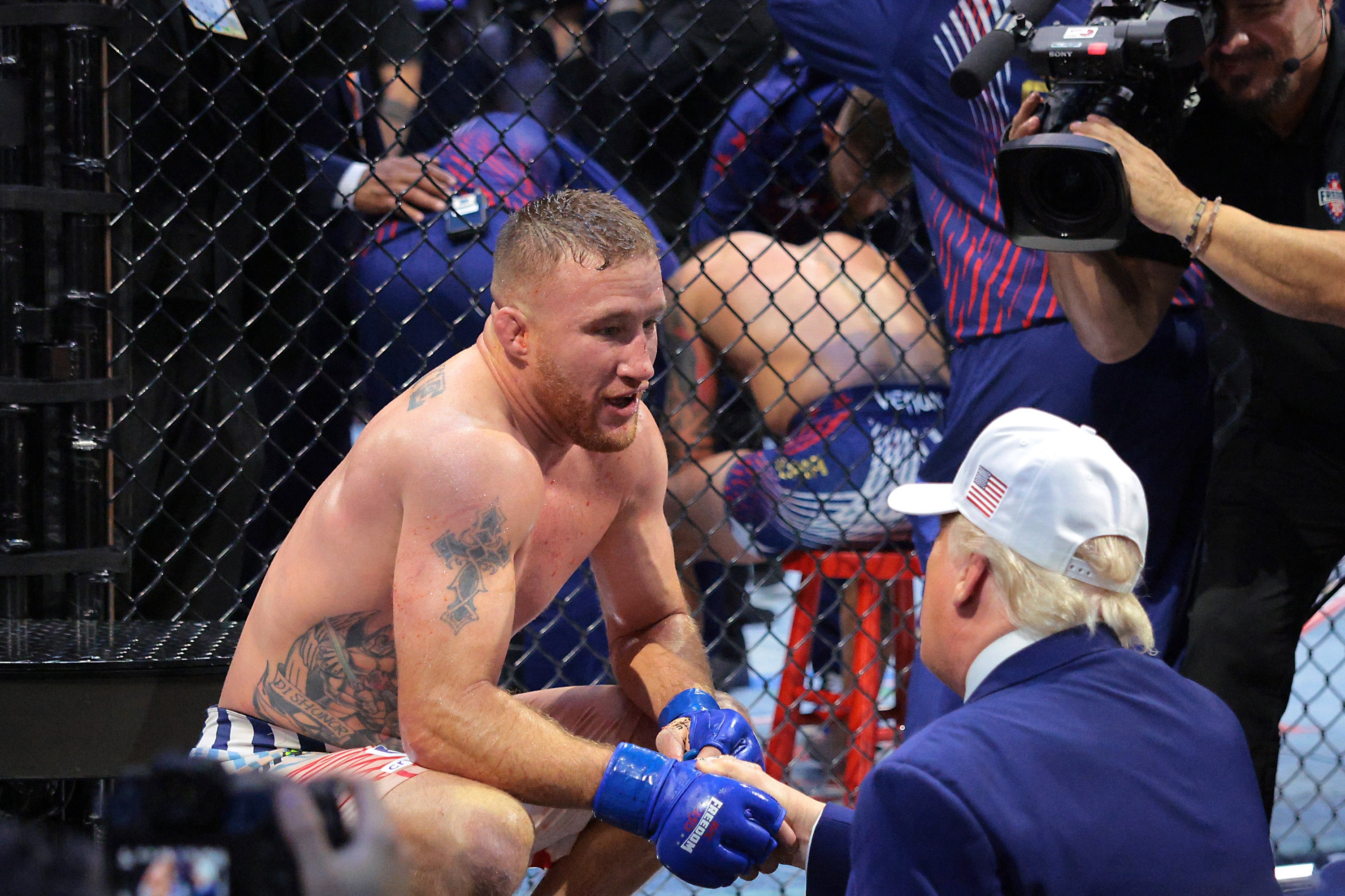 MMA combatant sitting successful a cage talking to a antheral successful a suit and cap. Photographer and unit around
