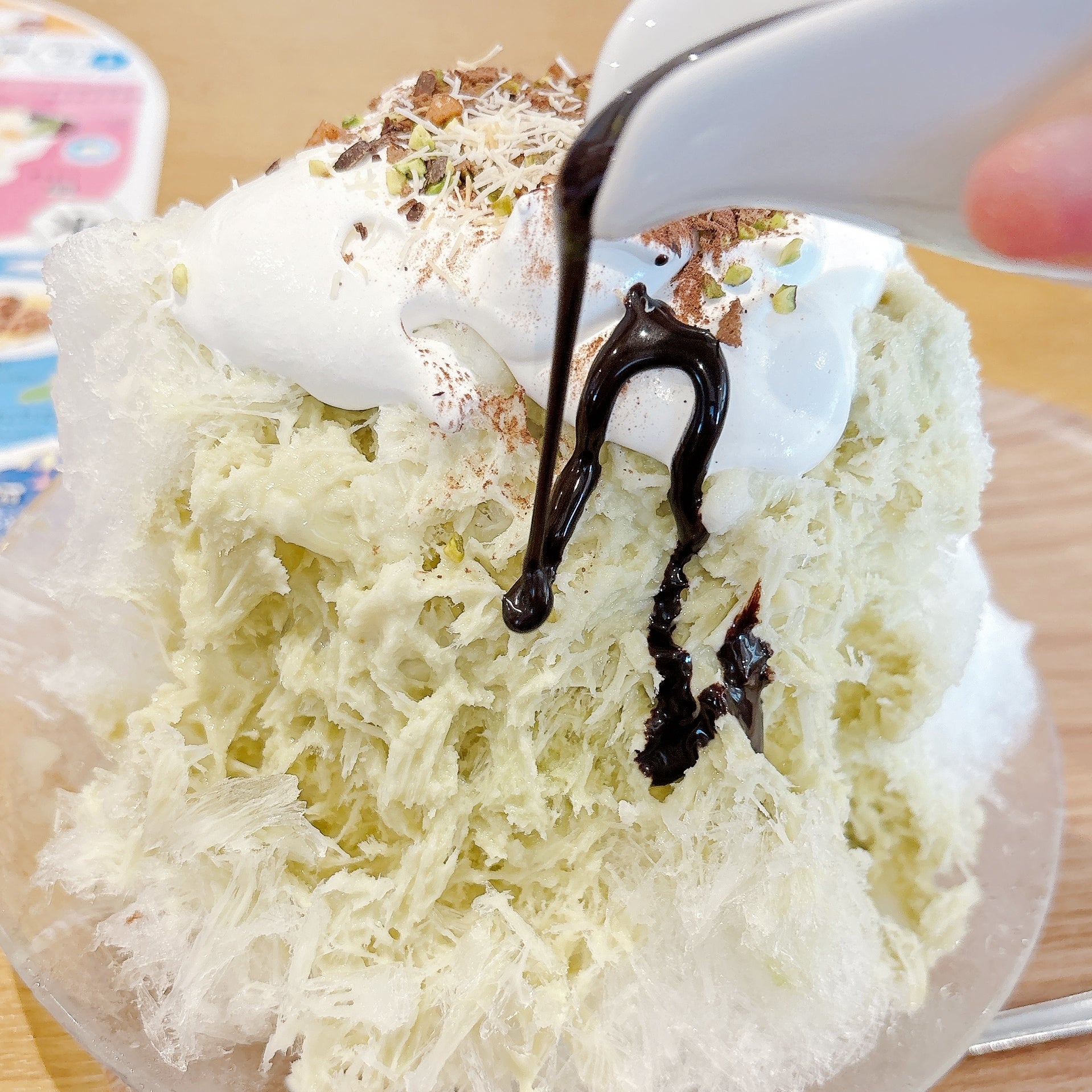 ココスの「純氷ふわふわかき氷 ドバイチョコ」かき氷にチョコレートソースをかけている様子。