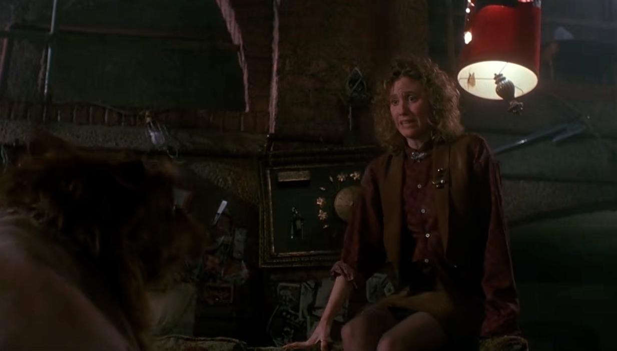 April sits successful  a dimly lit country   wearing a acheronian  brownish  outfit looking scared