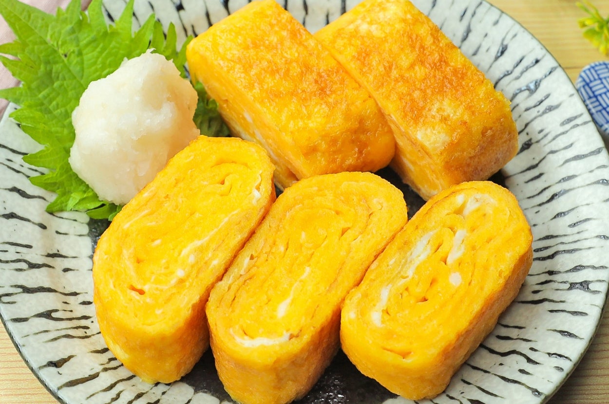 卵焼きが盛られた模様付きの皿。大根おろしと葉っぱが添えられている。