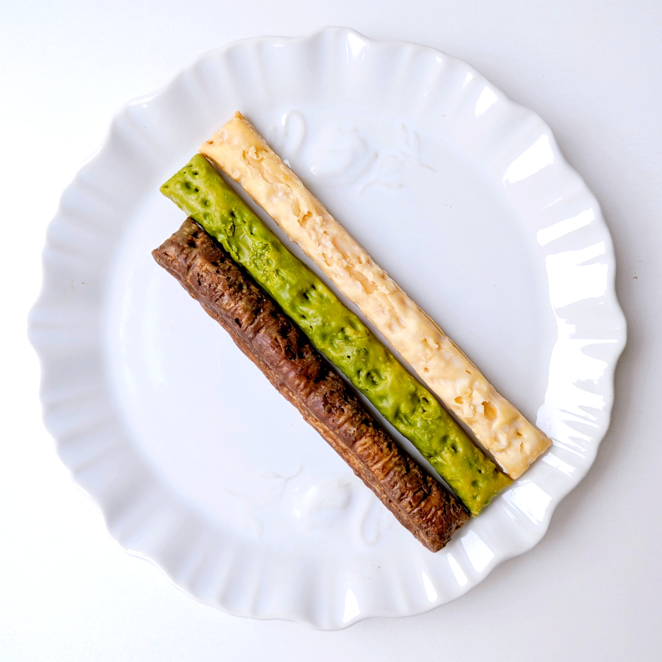 coneri（コネリ）「チョコレートスティックパイ」3本の異なるフレーバーのチョコスティックパイが白い皿に並べられている。