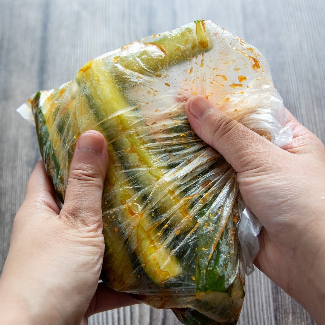 両手で袋に入った調味料で味付けしたきゅうりをもみ込んでいる。