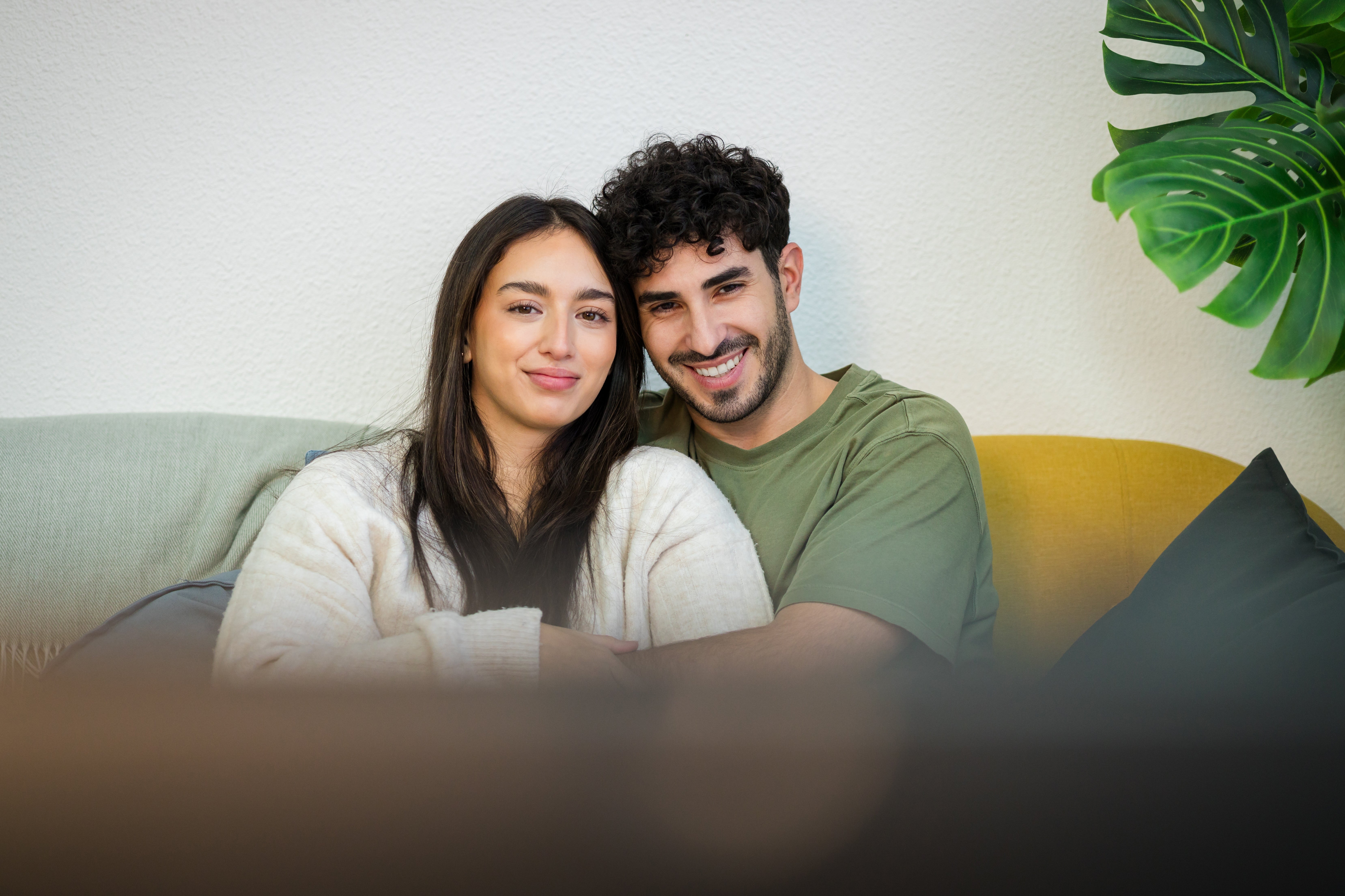 Couple sitting on a couch, smiling and embracing, conveying warmth and intimacy