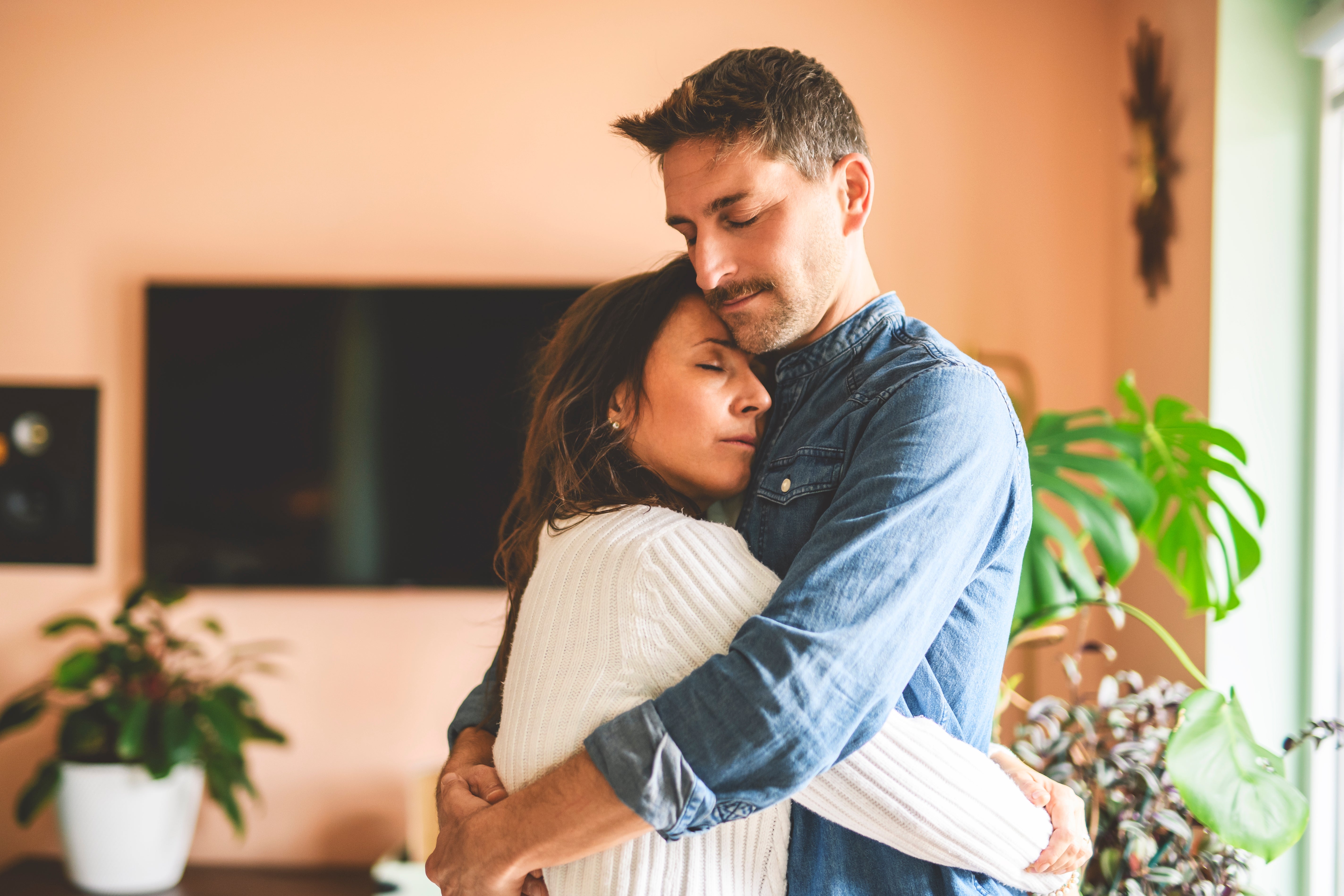 A couple embraces tenderly in a cozy room, conveying intimacy and affection