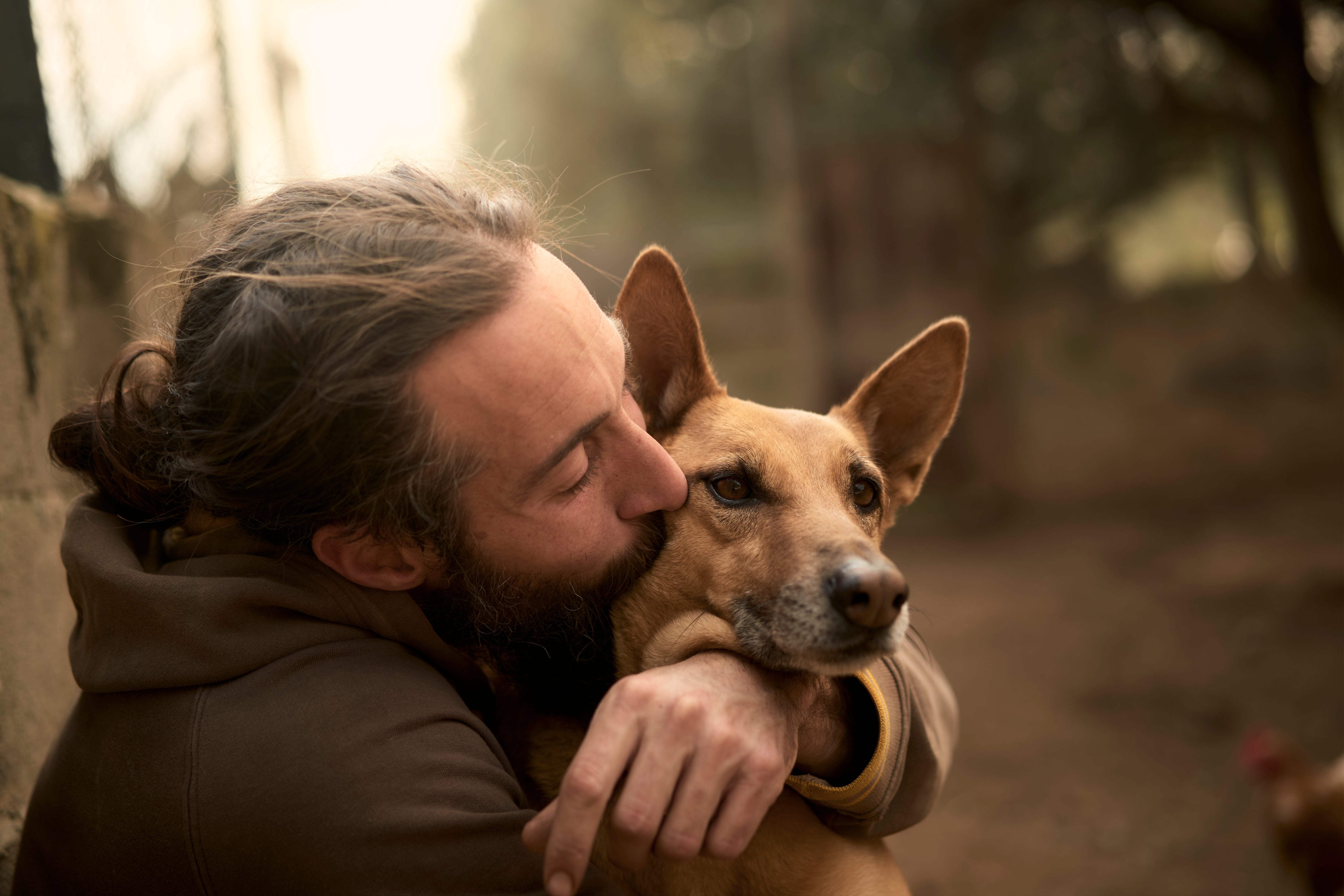 A person lovingly embraces a dog, sharing a tender moment outdoors