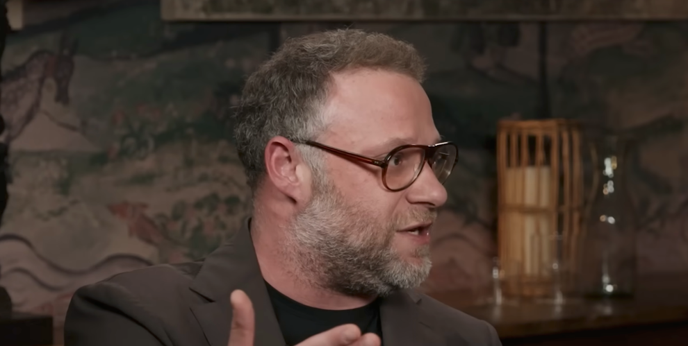 A person with glasses and a beard speaks animatedly during an indoor interview