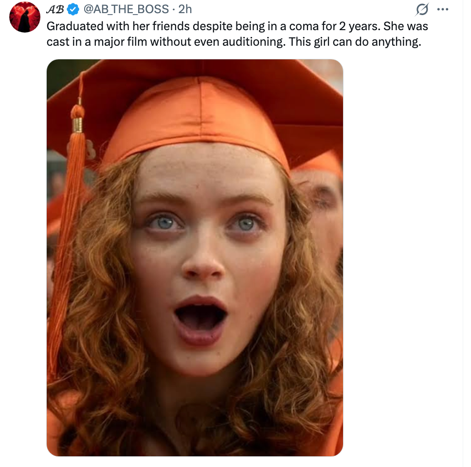 A amazed postgraduate wearing an orangish headdress and gown, with an look of astonishment and excitement
