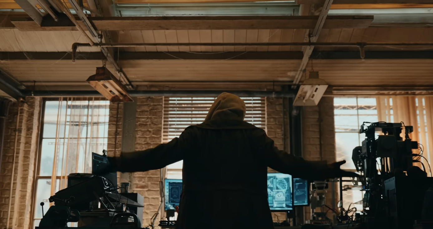 Person with hood facing machine screens successful a high-tech, industrial-style room