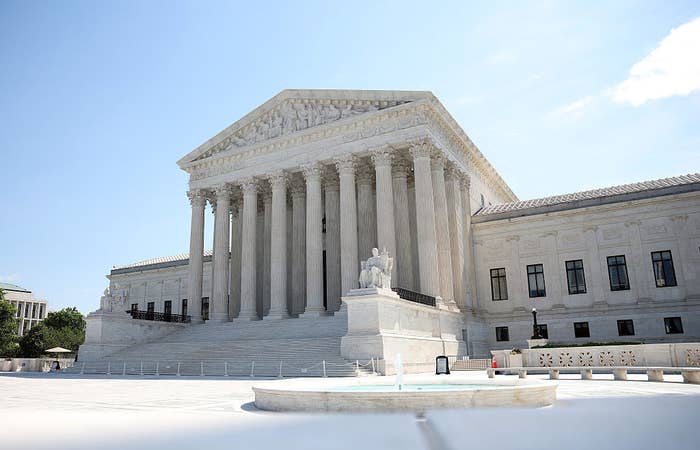 Gambar tersebut memperlihatkan bagian luar gedung Mahkamah Agung Amerika Serikat dengan tiang dan tangga ikoniknya, di bawah langit cerah