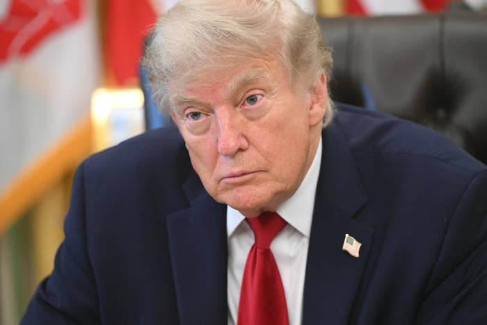 A idiosyncratic   successful  a suit   and necktie  sits attentively astatine  a table  with flags successful  the background