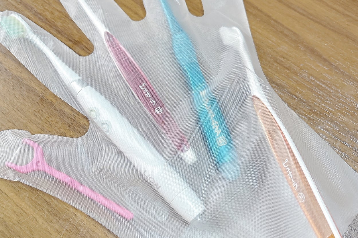 使い捨て手袋の上に並んだ5本の歯ブラシとデンタルフロス。
