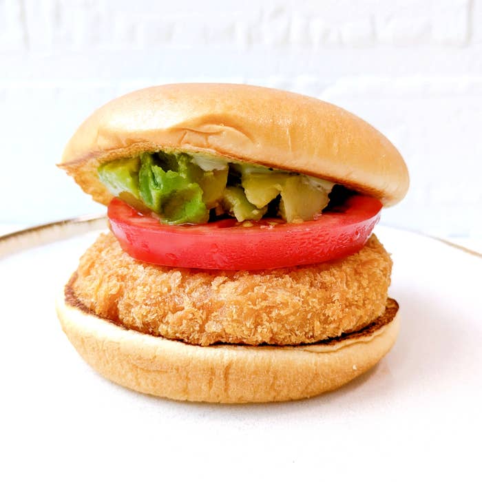 モスバーガー「アボカド海老カツバーガー ～国産バジルマヨ～」ハンバーガーの中に海老カツ、トマト、アボカドが挟まれている。