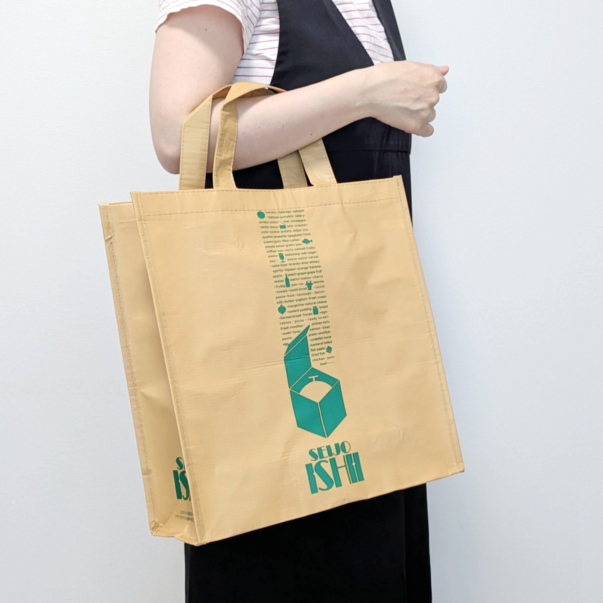 成城石井「リサイクルエコバッグ」「SEIJO ISHII」のロゴが入ったエコバッグを持っている。