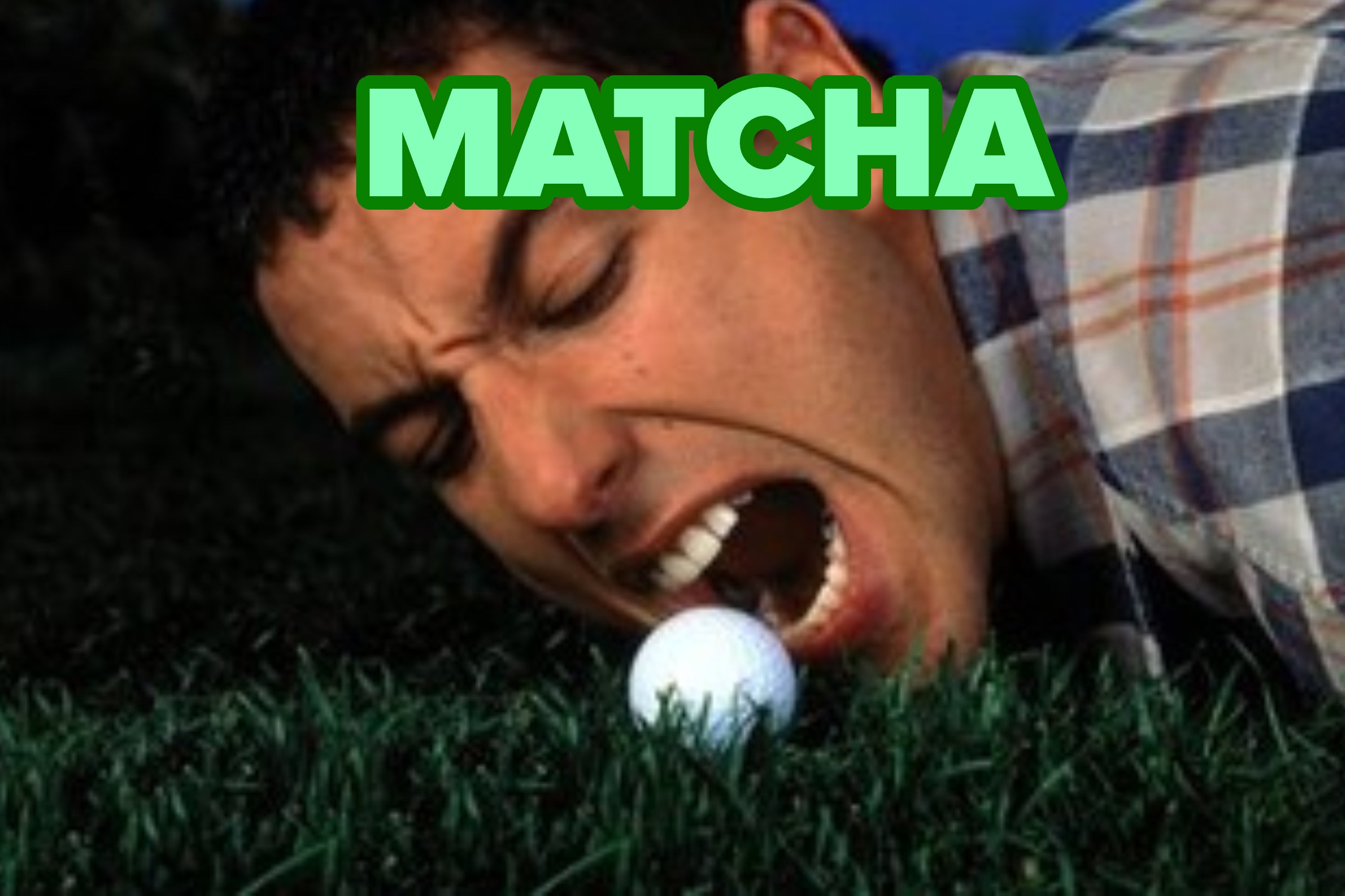 A person lying on grass, humorously preparing to bite a golf ball