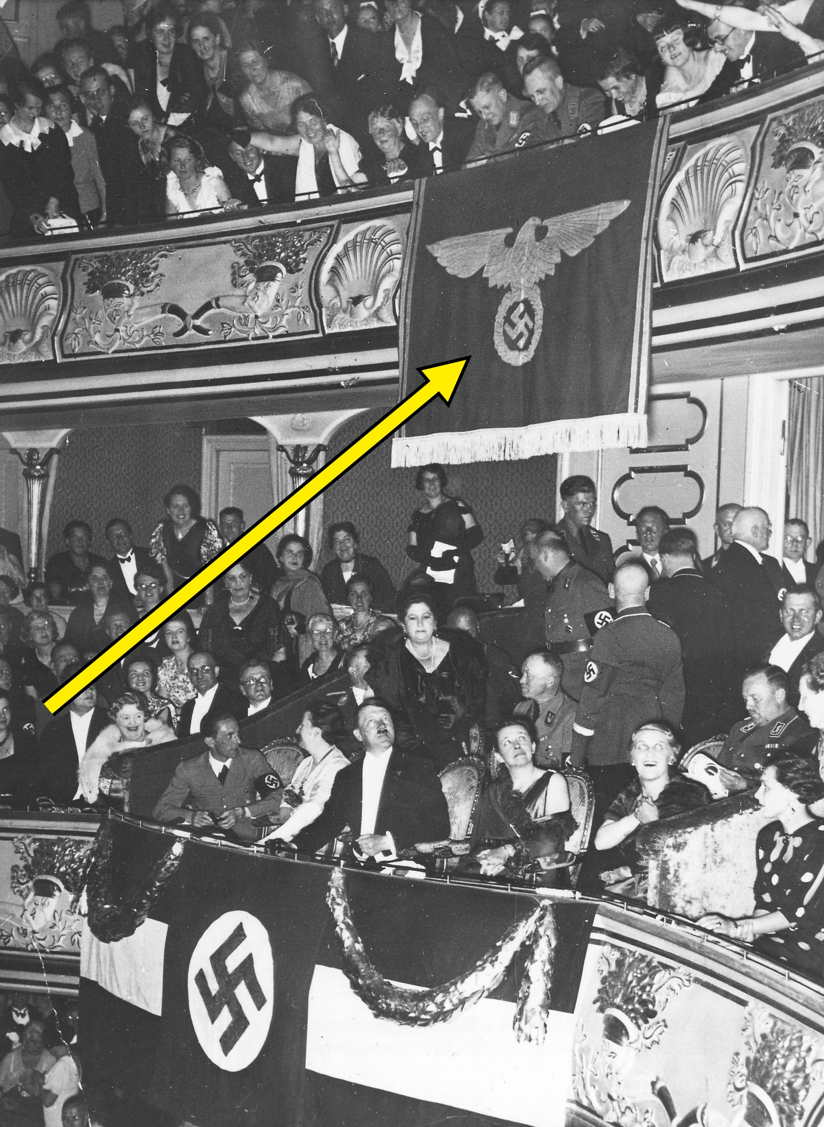 Audience successful theatre with Nazi emblems displayed prominently, showing Nazi officers and civilians successful attendance