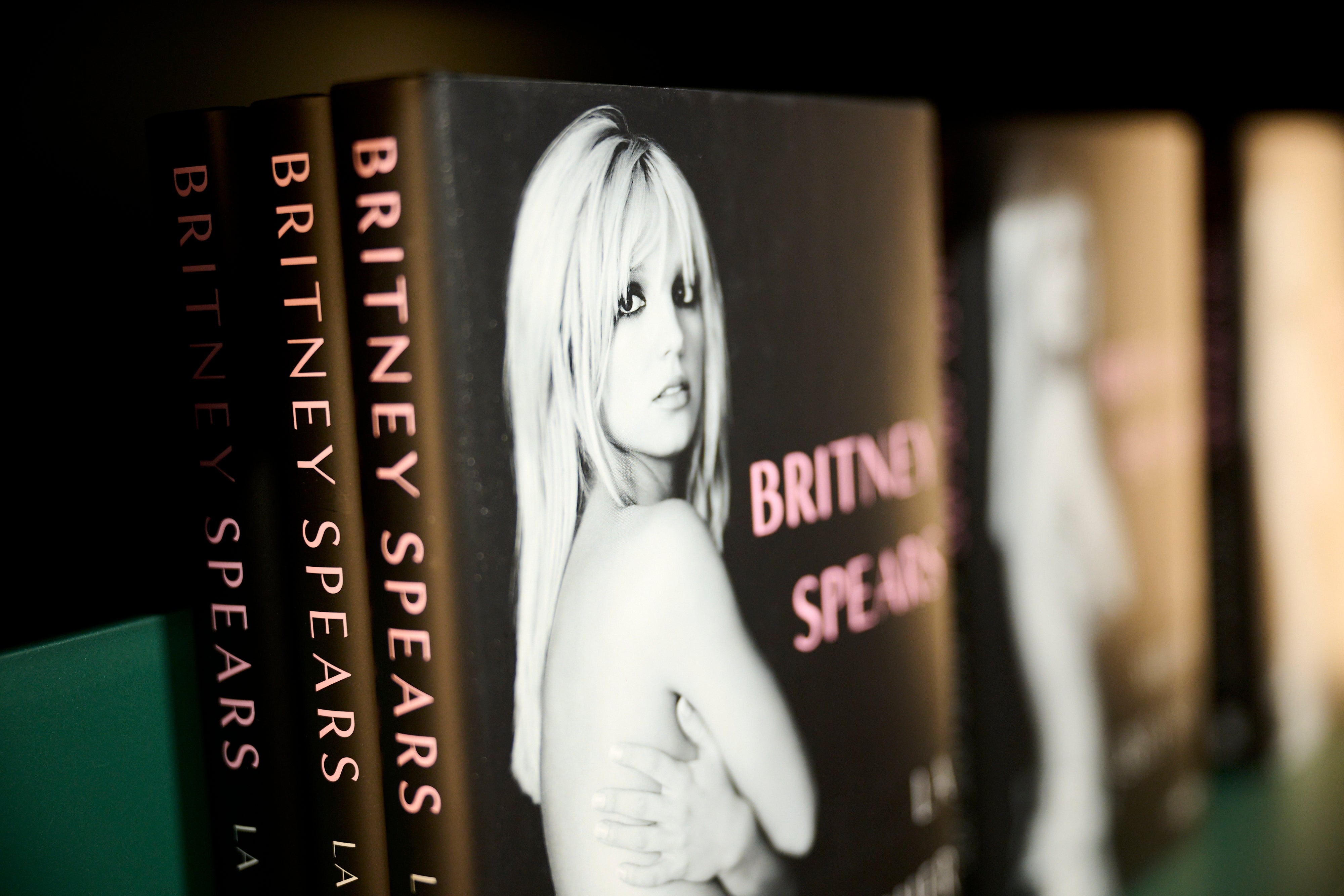 Books on a shelf show the cover of a biography with a black-and-white photo of a woman and the text "Britney Spears."