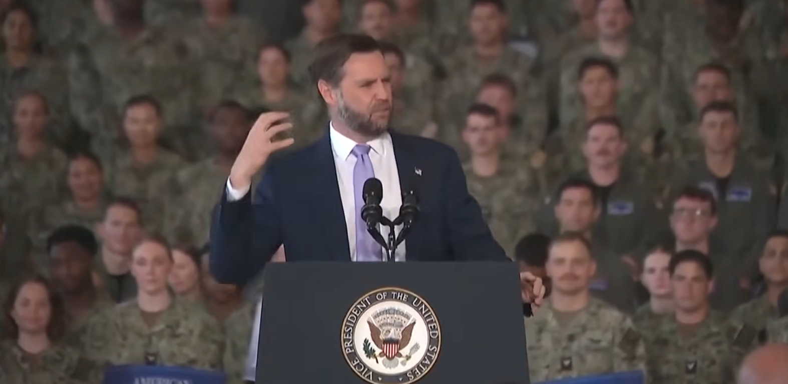 A antheral speaks astatine a podium with the U.S. Vice Presidential seal, addressing a radical of subject unit successful uniform