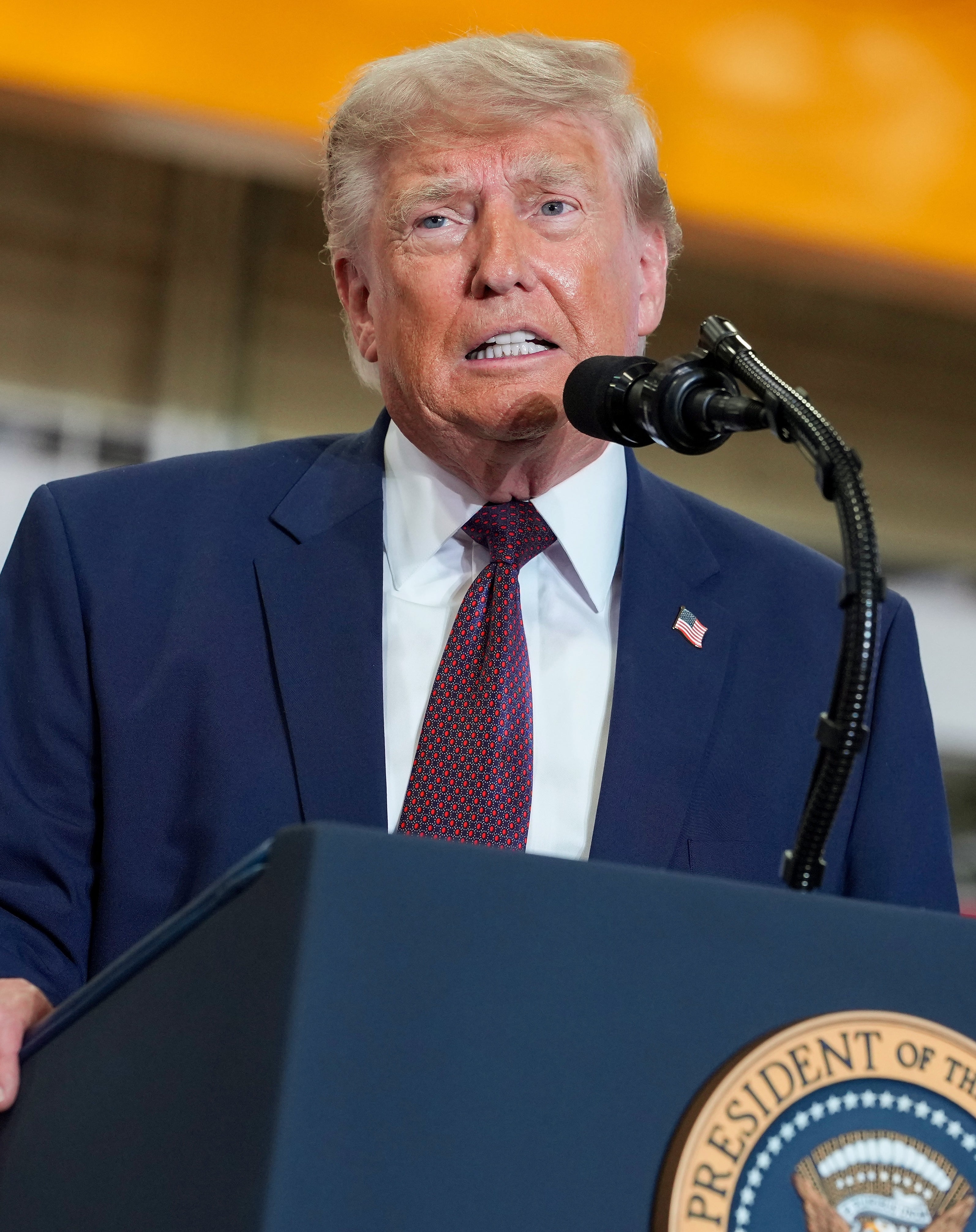 A idiosyncratic successful a suit speaks astatine a podium with a seal. The mounting appears to beryllium a nationalist lawsuit oregon property conference