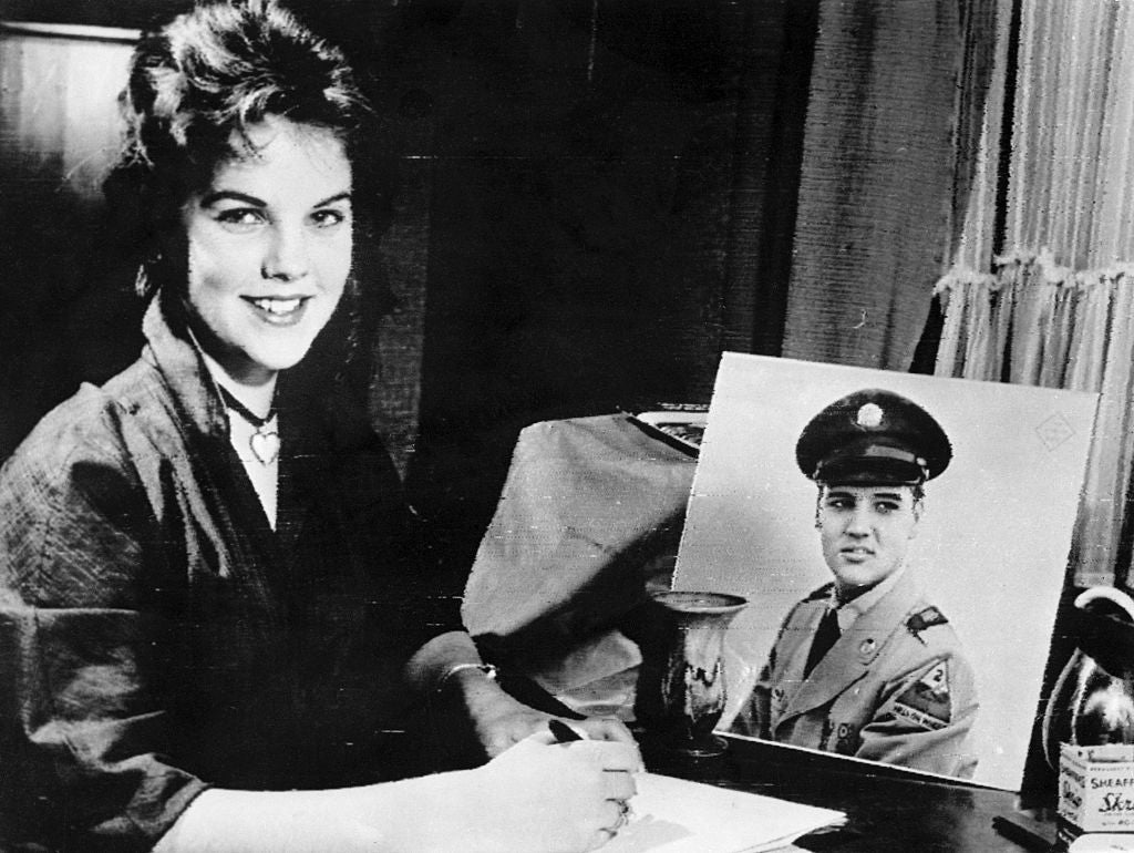 Sixteen year old Priscilla Beaulieu sits before a portrait of a uniformed Elvis Presley as she writes him a letter