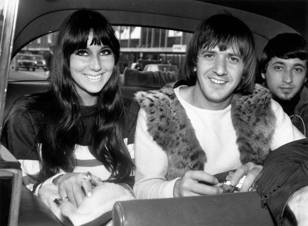 Sonny and Cher sit in a car in a vintage photograph, both smiling