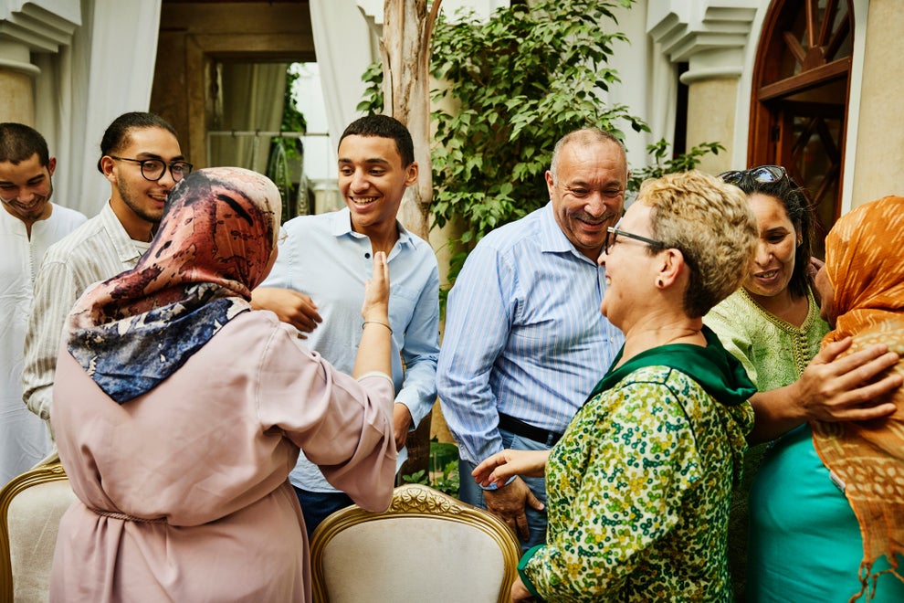A joyful group of adults in casual attire are socializing and embracing at a gathering, conveying a sense of warmth and connection