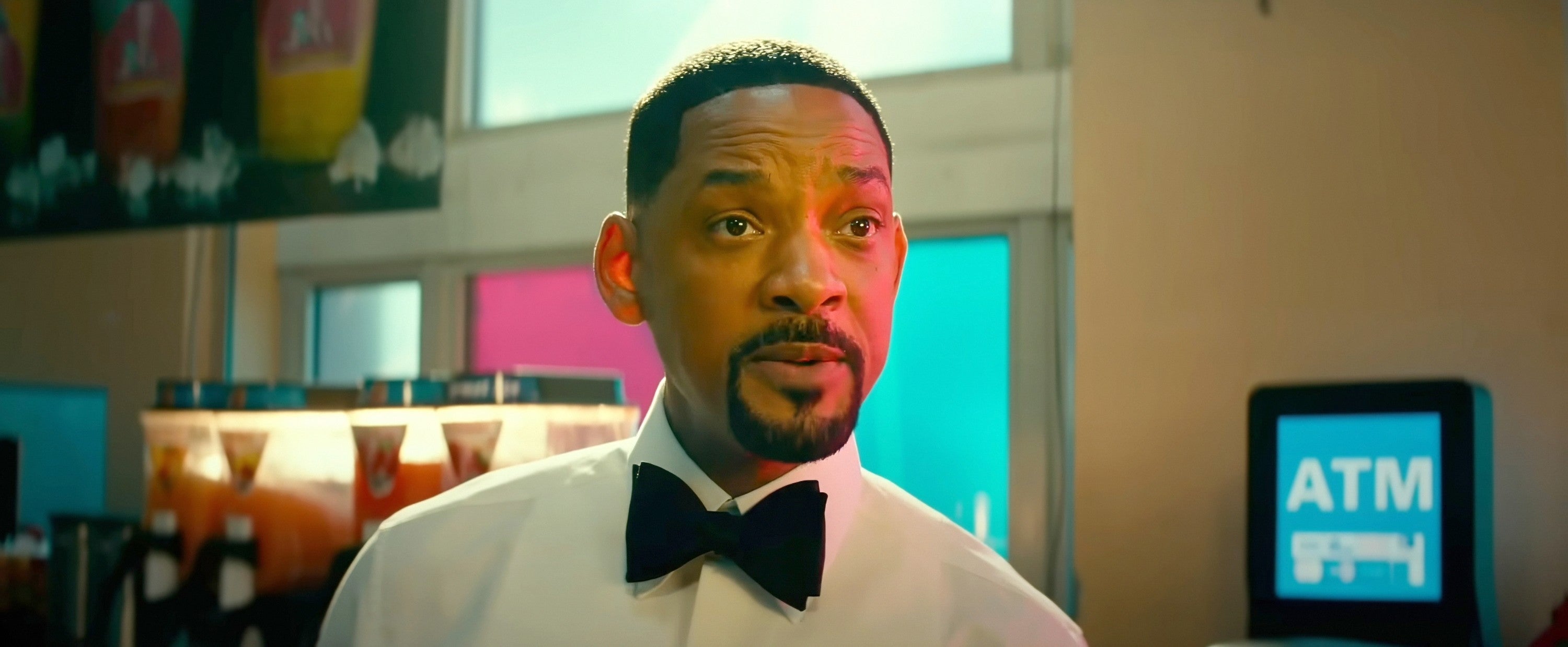 Will Smith wearing a formal white shirt and black bow tie stands by an ATM, appearing to converse in a scene