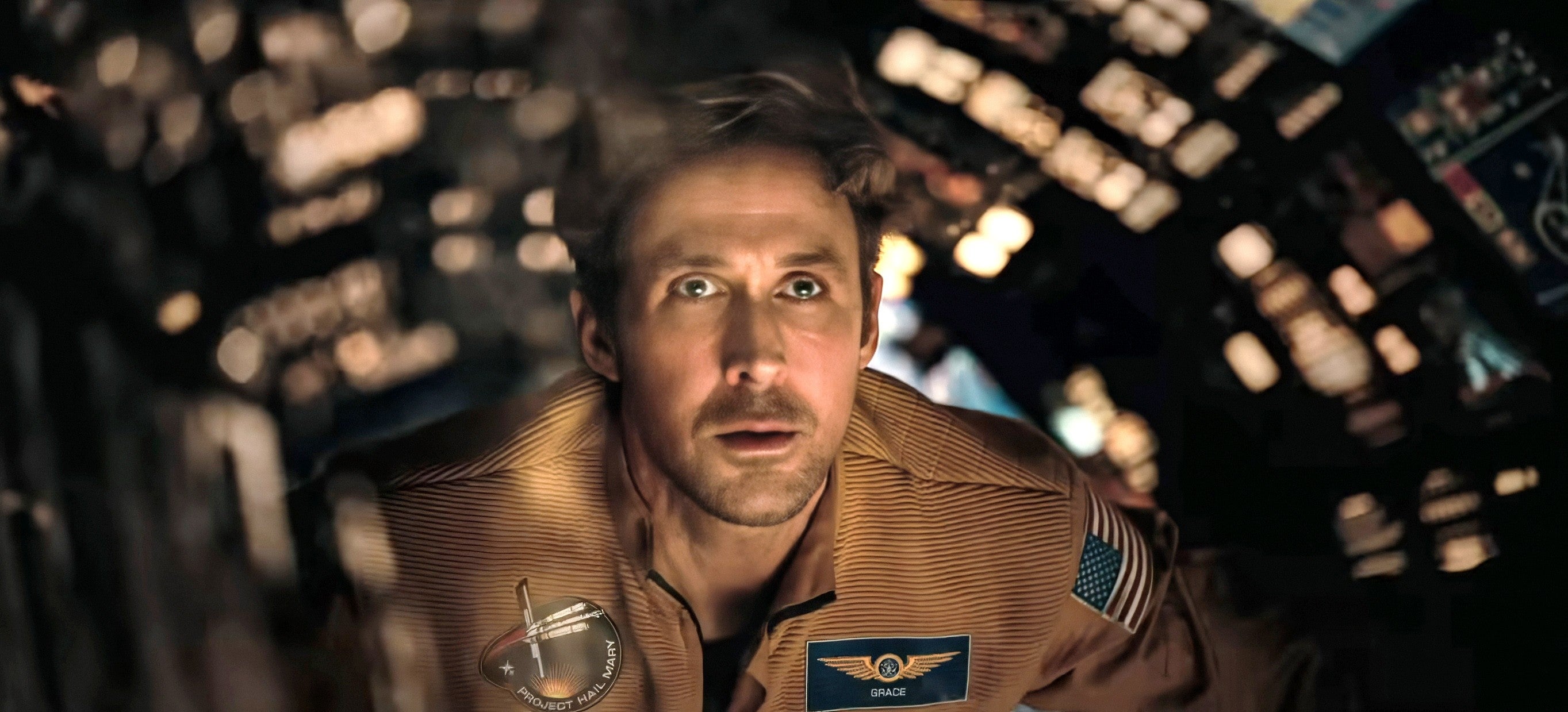 Ryan Gosling wearing a flight suit is inside a spacecraft cockpit, looking forward with an expression of focus and determination
