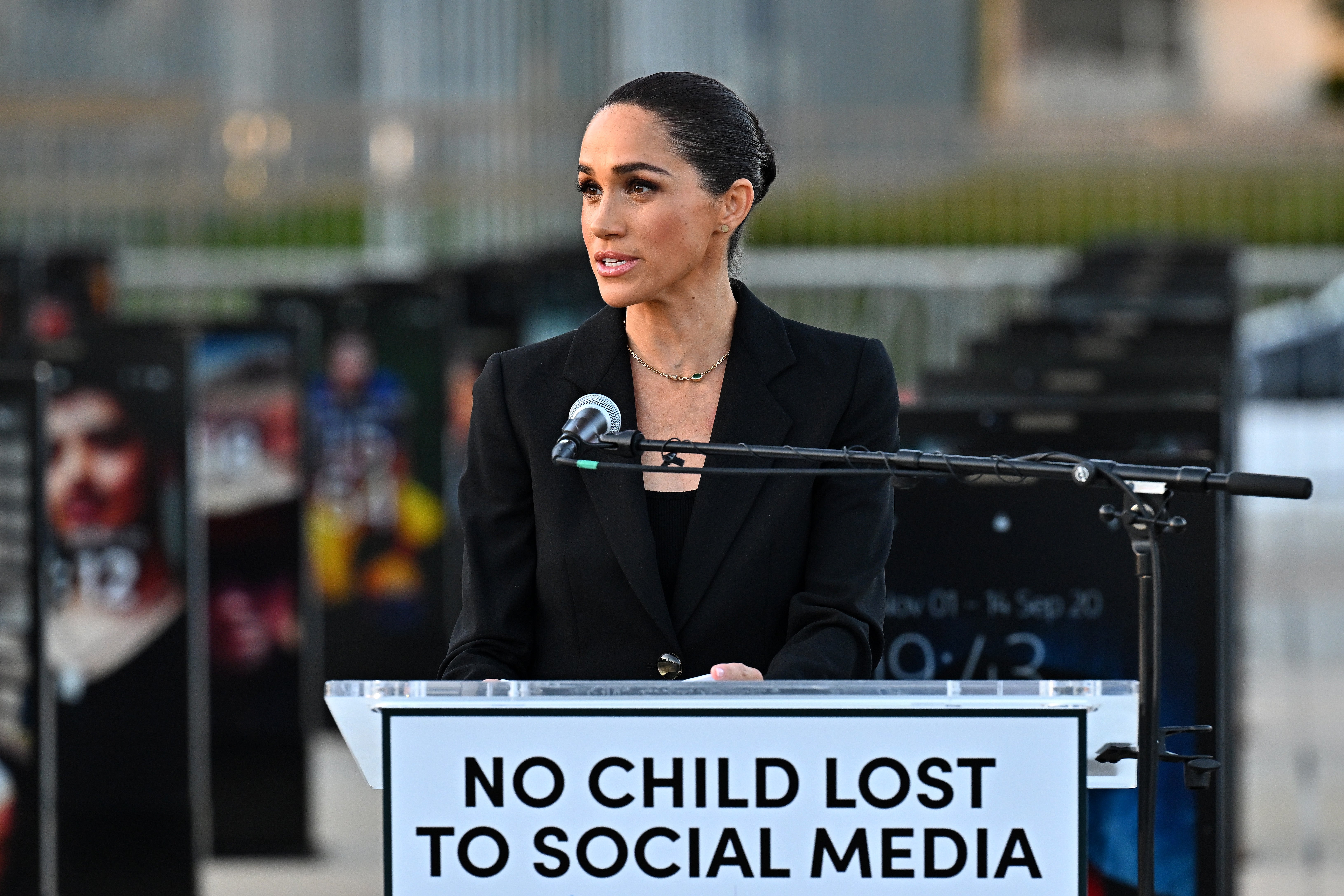 A person speaks at a podium with a sign reading "No Child Lost to Social Media" at an outdoor event