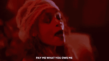 Person with dramatic expression, wearing a netted headpiece, says, "PAY ME WHAT YOU OWE ME," emphasizing urgency or demand