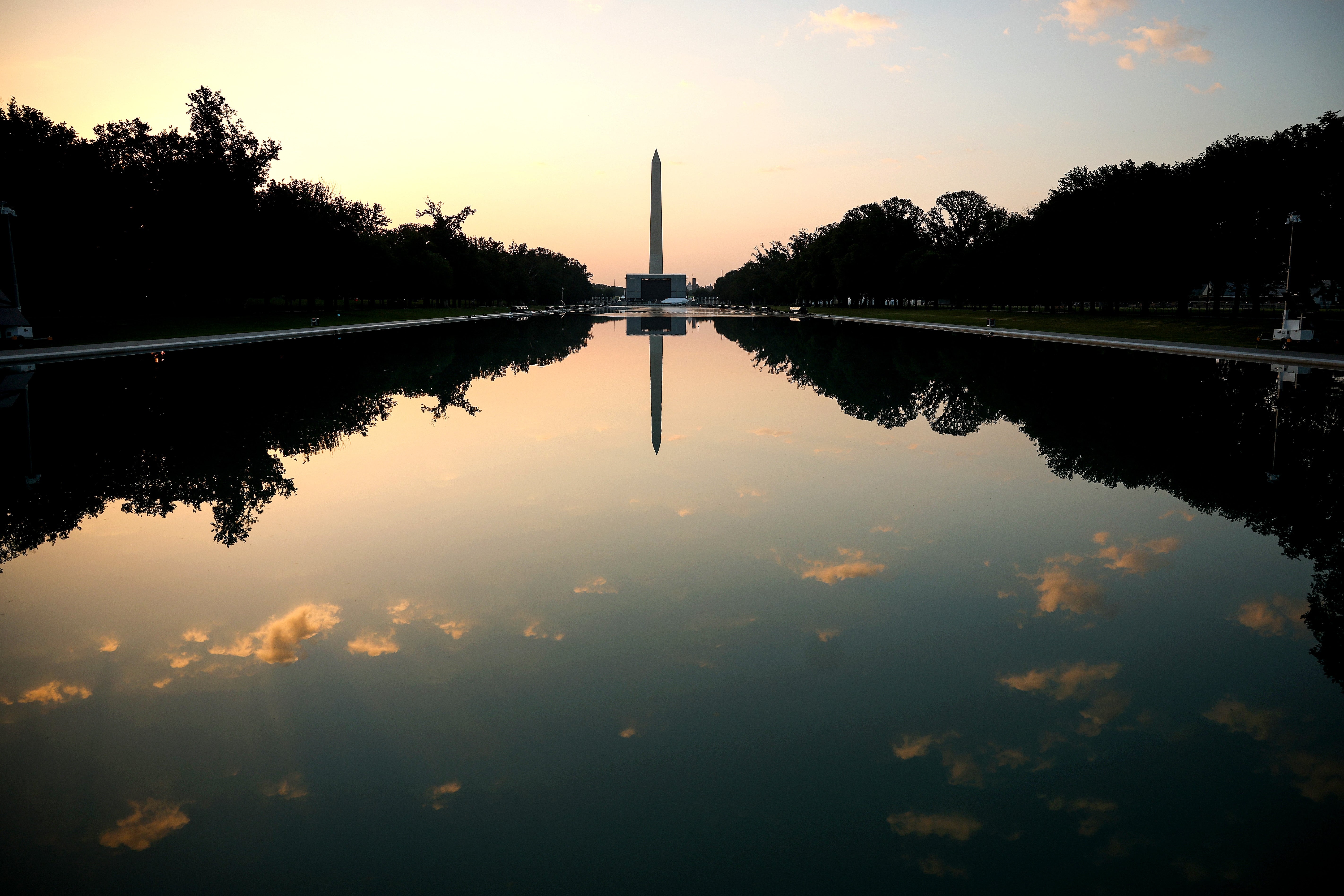 Washington Monument reflected successful the Reflecting Pool astatine sunrise, framed by trees