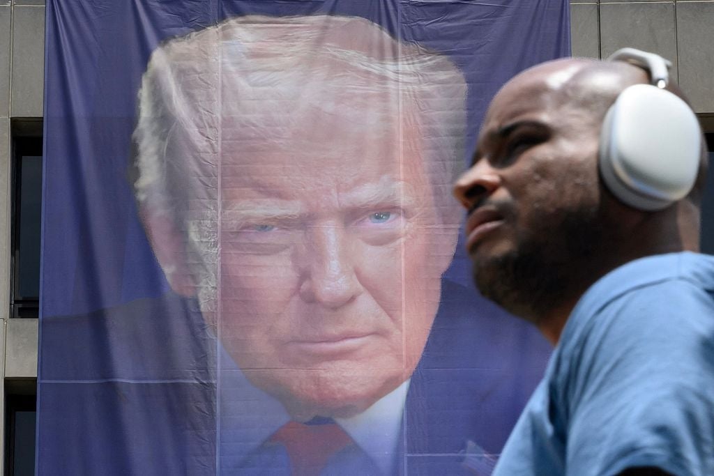 Man wearing headphones walks past a ample banner with a look print