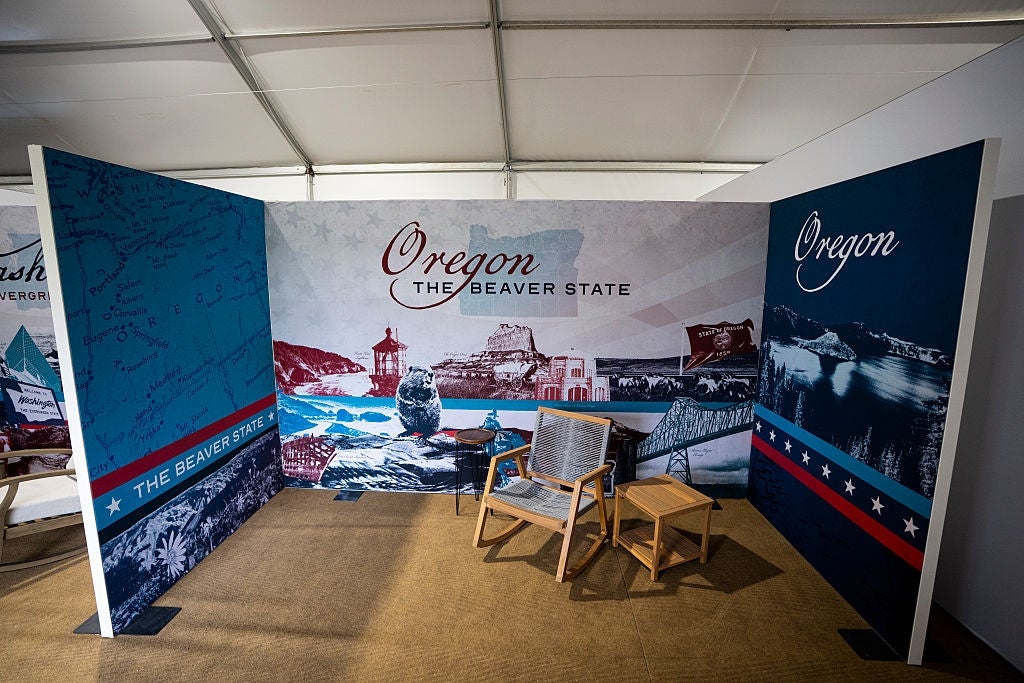 Exhibit booth showcasing Oregon arsenic "The Beaver State" with scenic photos, a chair, and tiny array successful a tented show area